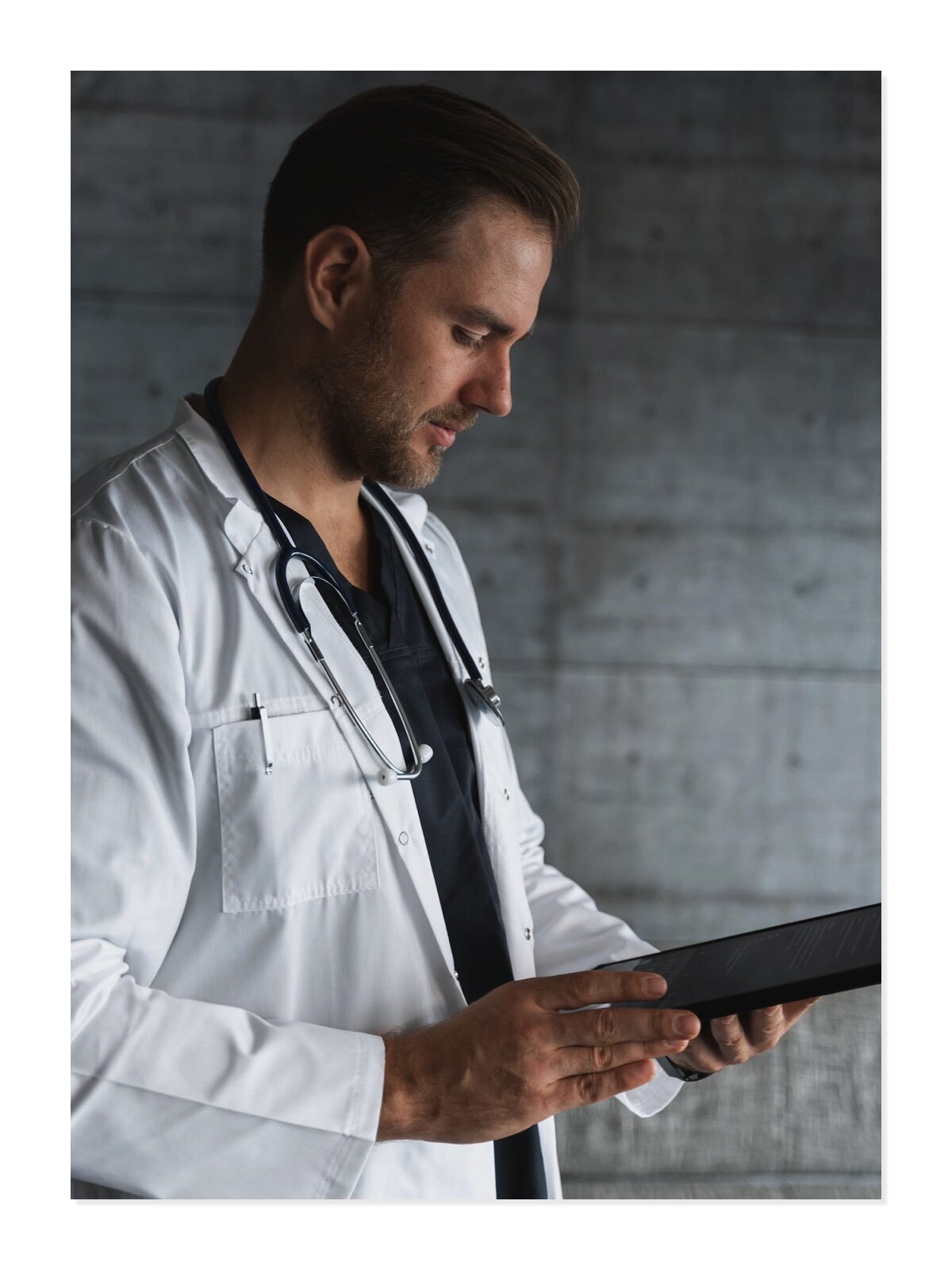 Fotografia przedstawia mężczyznę wykonującego zawód lekarza. Jest ubrany w szpitalny kitel oraz specjalną osłonkę na głowę. Znajduje się na sali operacyjnej.