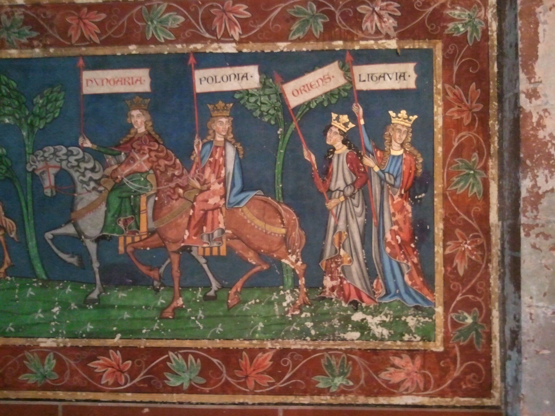 Ilustracja przedstawia fragment fresku, na którym uwidoczniono czterech władców. Dwóch z nich, od lewej strony, jedzie konno, pozostali dwaj idą za nimi pieszo. Wszyscy ubrani są w bogate szaty, na głowach mają korony. W rękach trzymają uniesione do góry sztandary z napisami od lewej Dvngaria, Polonia, Oriens, Ligavia. Znajdują się na zielonym polu, pomiędzy jest wysoka roślinność. Całość zwieńczona jest obramowaniem z motywem liści.