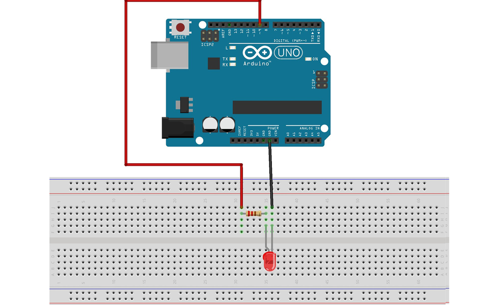 Ilustracja przedstawiająca płytkę Arudino oraz sześćdziesięciowierszową płytkę stykową. Z pinu Arduino podpisanego 9 poprowadzono czerwony przewód, którego drugi koniec umieszczono na płytce stykowej w otworze J31. Ze złącza GND na Arduino poprowadzono czarny przewód, którego drugi koniec umieszczono na płytce stykowej w otworze J36. Na płytce stykowej znajduje się rezystor oraz czerwona dioda LED. Rezystor posiada kolejno oznaczenia: czerwony, czerwony, brązowy, złoty. Pierwsza nóżka rezystora wpięta jest w otworze I31, a druga w otworze I35. Pierwsza noga diody LED wpięta jest w otworze G35, a druga w otworze G36.