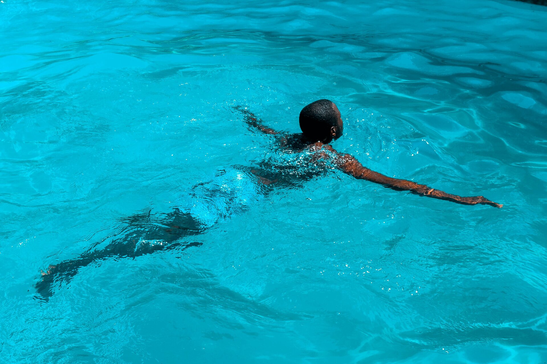 Ilustracja przedstawia chłopca pływającego w basenie.