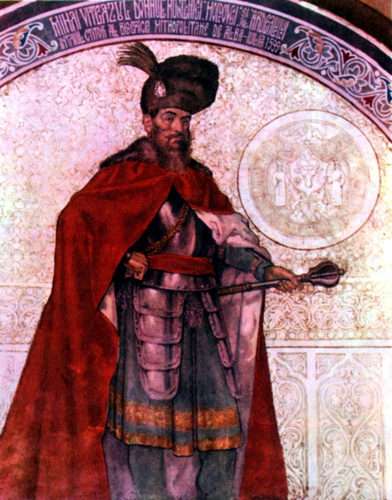 Ilustracja przedstawia starszego mężczyznę o ostrych rysach twarzy. Ma ciemne, krótkie włosy, wąsy i długą brodę, groźne spojrzenie i orli nos. Na głowie duża, futrzana czapka z przyczepionym piórkiem. Ubrany jest w szatę do kolan, spodnie oraz długi, czerwony płaszcz z futrzanym kołnierzem. Na piersiach ma zbroję. W lewej ręce trzyma berło, a prawą ma podpartą na biodrze.