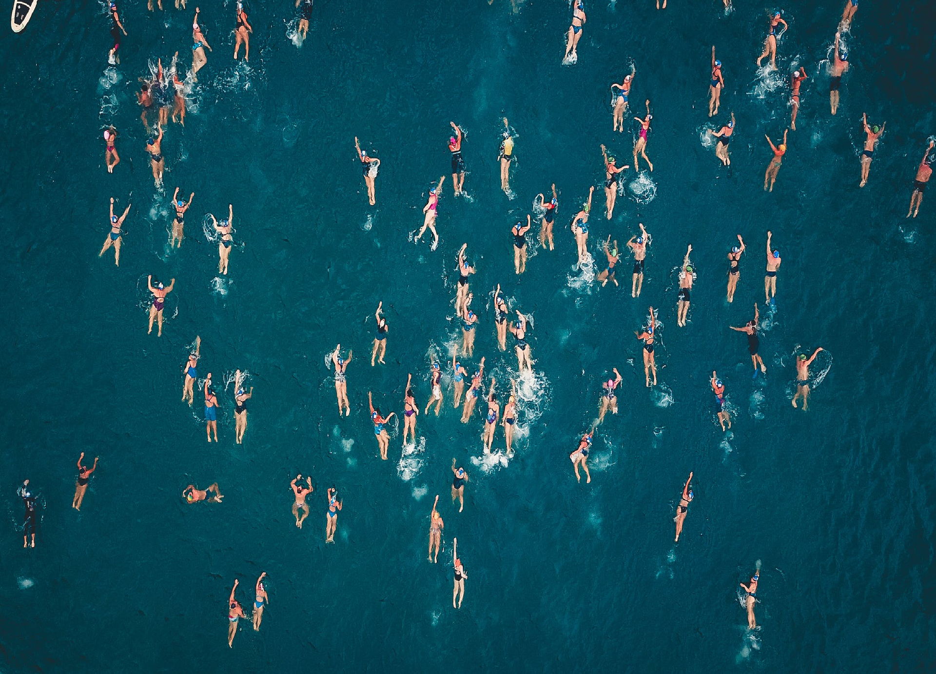 Zdjęcie wykonano z lotu ptaka i ukazuje pływające osoby w zborniku wodnym.
