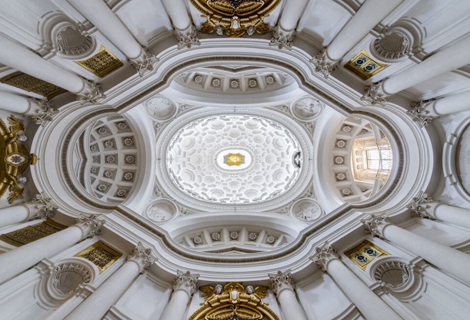 Zdjęcie o kształcie poziomego prostokąta przedstawia wnętrze kopuły San Carlo alle Quattro Fontane. Nawę główną, która ma rzut zbliżony do elipsy, okalają nieregularne kaplice i zakrystia. Owalne wnętrze przykrywa piękna kasetonowa kopuła. Charakteryzuje się geometrycznym wzorem z oknami otoczonymi fantazyjnymi ornamentami. Od elipsy biegną korynckie, białe kolumny ze złoconymi kapitelami.