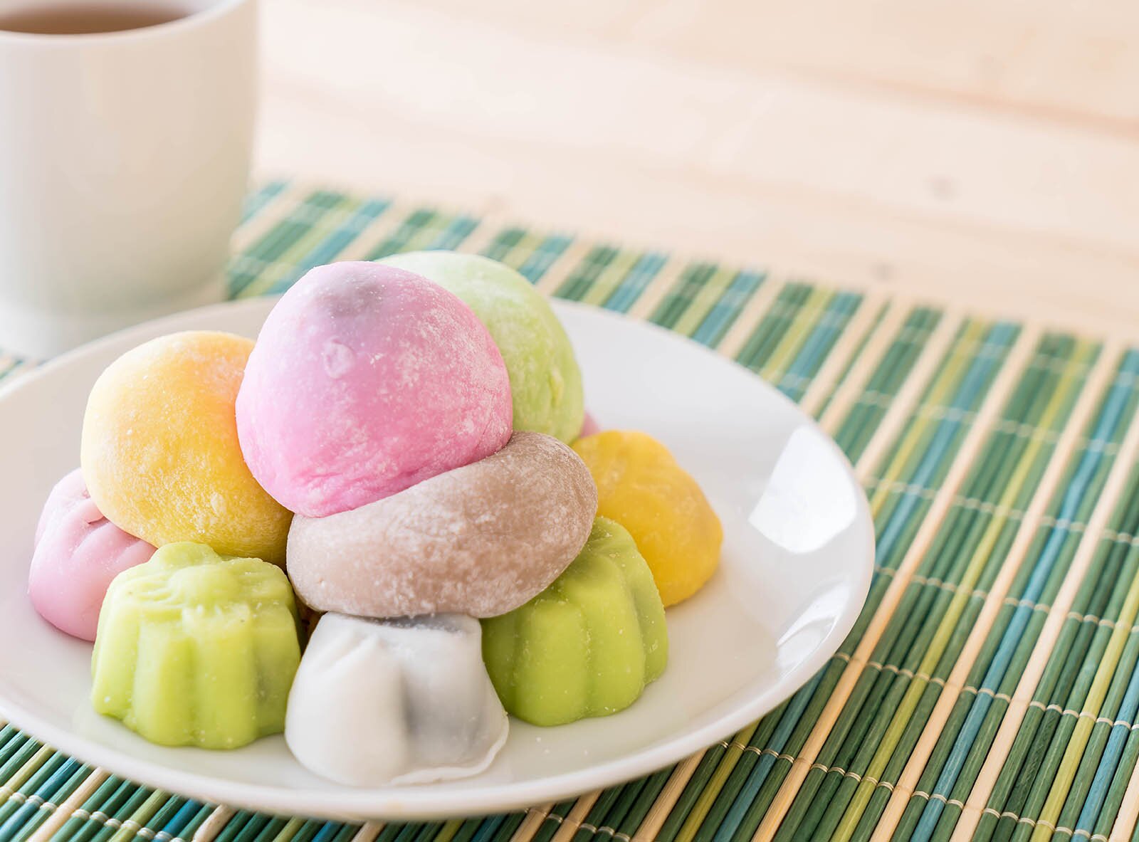 Zdjęcie przedstawia tradycyjne ciastka japońskie. Wyglądają jak okrągłe pufki w pastelowych kolorach. 