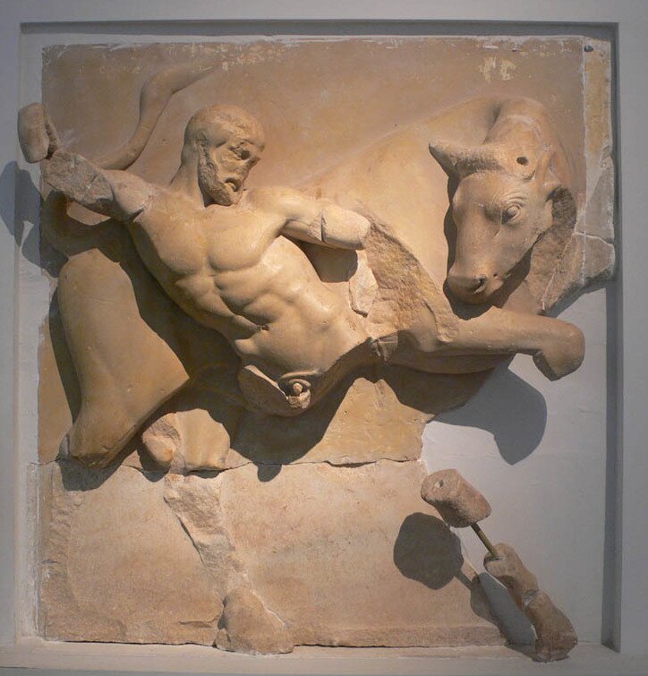Na zdjęciu znajdują się fragmenty zniszczonej rzeźby przedstawiającej umięśnionego mężczyznę walczącego z bykiem.