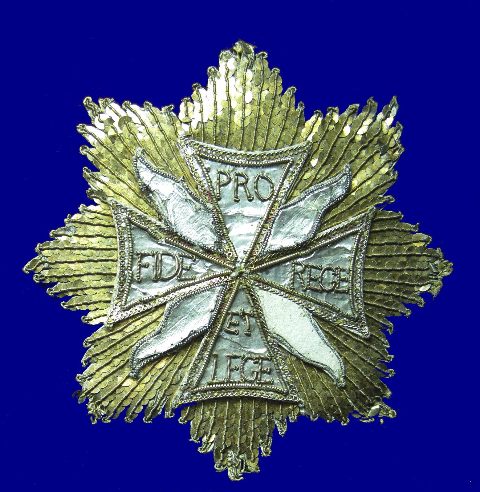 Na zdjęciu order Orła Białego. W środku krzyż o równych ramionach. Na górnym ramieniu napis PRO, na dolnym ET LEGE, na lewym FIDE, na prawym REGE. Za krzyżem jest 8 ramienny liść. 