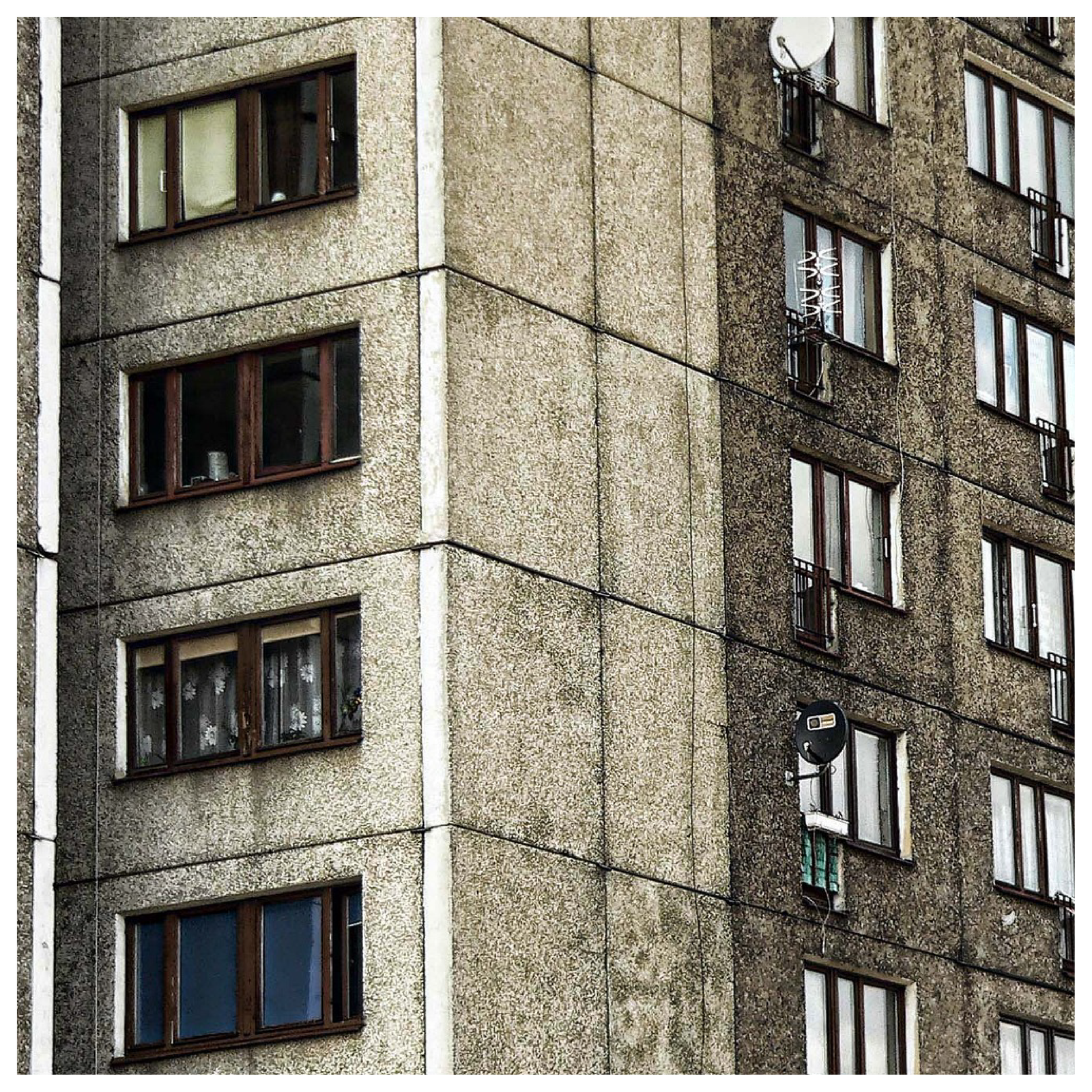 Na zdjęciu znajduje się fragment dużego bloku mieszkalnego. Jest zaniedbany, brzydki, szary, stary, brudny i niewygodny. 