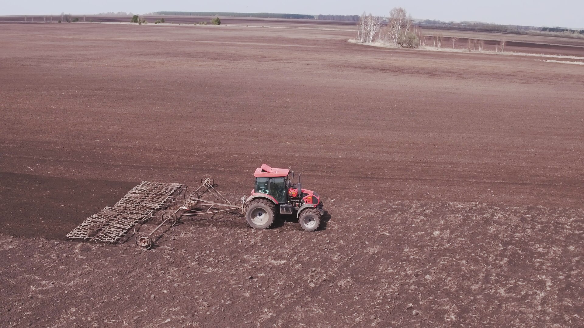 Zdjęcie ukazuje ciągnik, do którego zapięto brony. Narzędzie to składa się z dwóch ram wyposażonych w ostre kolce spulchniające glebę.
Nagranie tożsame z treścią opisu.