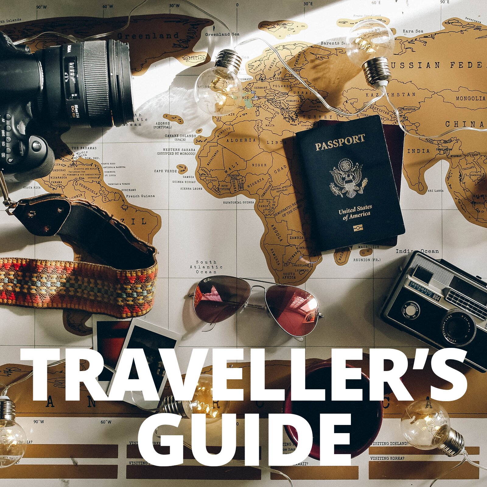 Zdjęcie przedstawia w tle rozłożoną mapę świata z zaznaczonymi kontynentami, na której widoczne są różne przedmioty związane z podróżowaniem: paszport z napisem w języku angielskim: PASSPORT United States of America, aparat fotograficzny na kolorowym pasku, radio na baterie, okulary przeciwsłoneczne. Na dole widoczny jest duży napis w języku angielskim: TRAVELLER'S GUIDE.