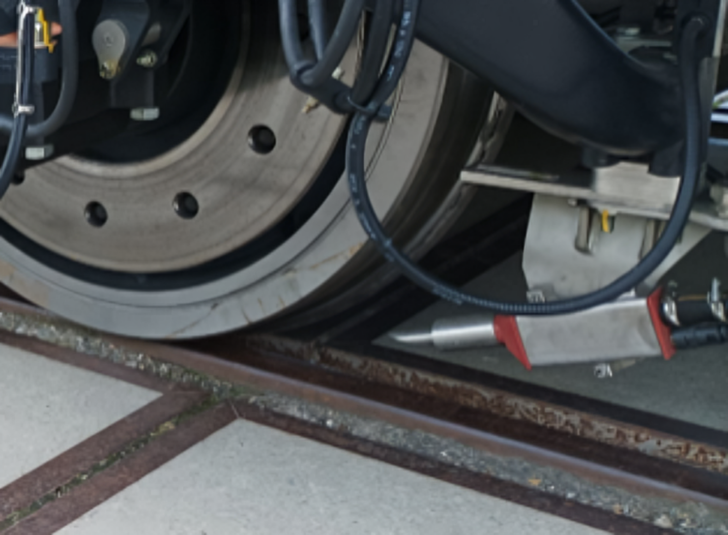 Ilustracja przedstawia zdjęcie piasecznicy. Element ten znajduje się przed kołem, tuż nad powierzchnią główki szyny. Piasecznica jest to podłużny element połączony przewodem z dziurą na końcu, przez który przepuszczany jest piasek na powierzchnię szyny.