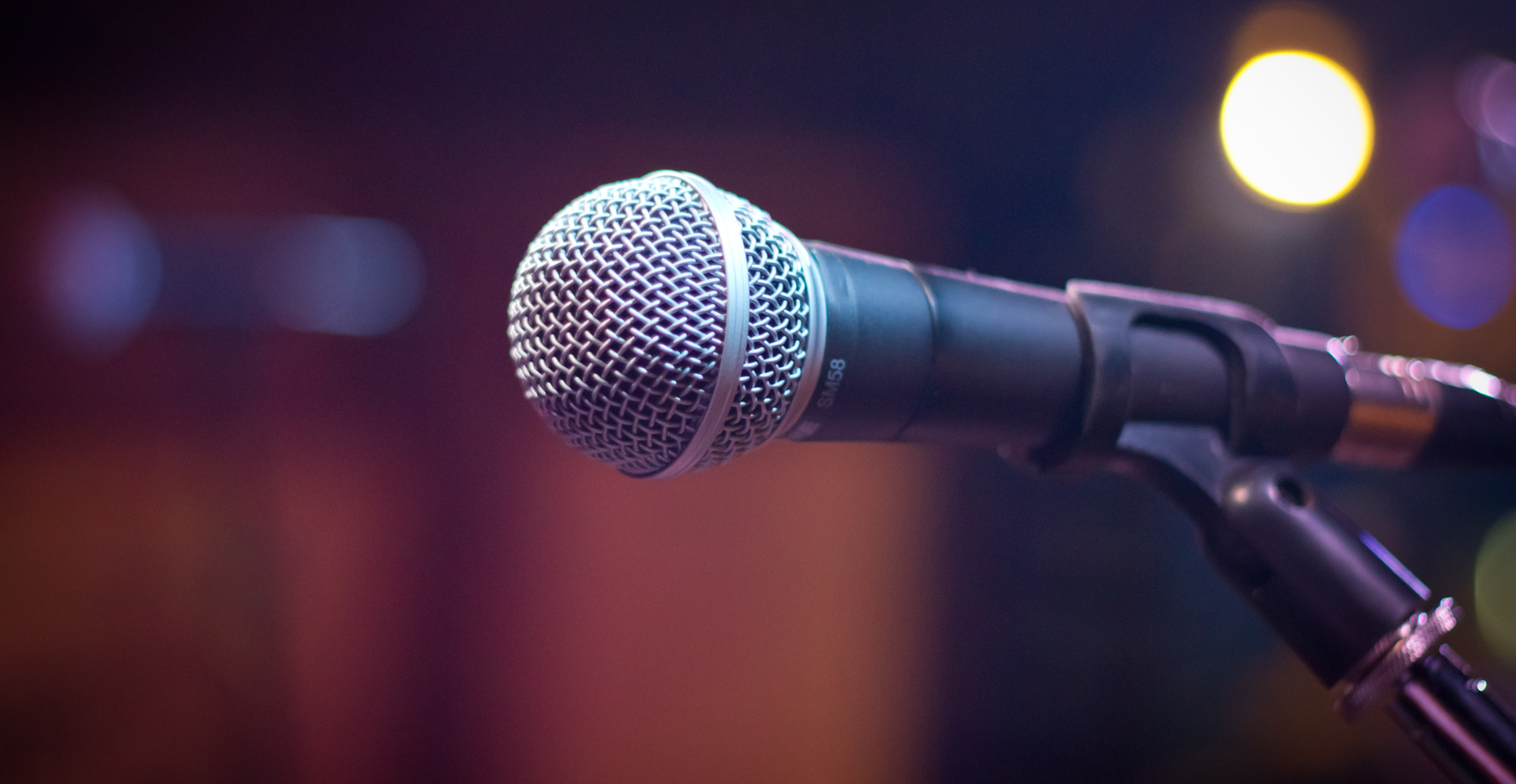 Zdjęcie przedstawia zbliżenie na mikrofon, który znajduje się w uchwycie statywu.