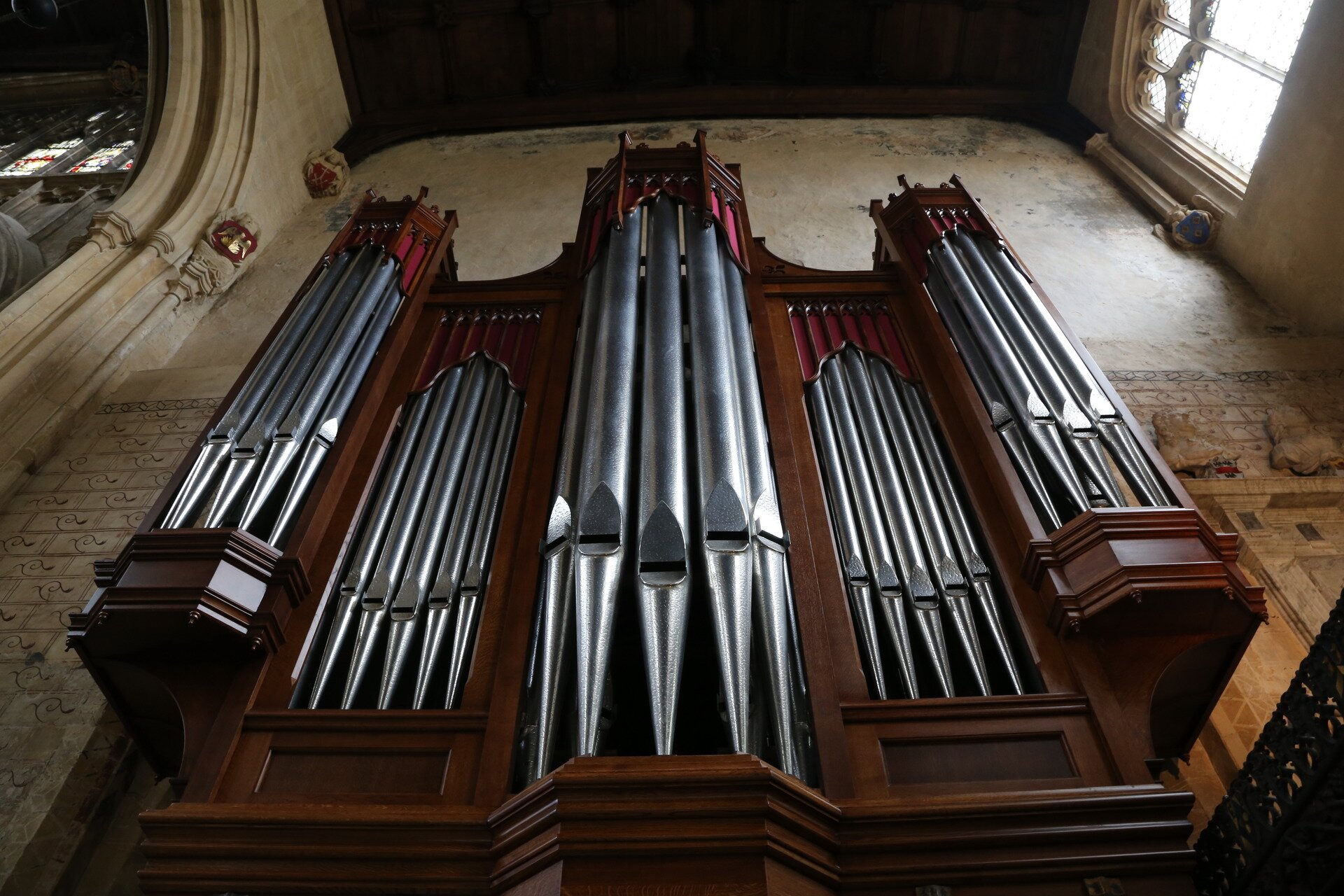 Ilustracja przedstawia organy kościelne. Organy wykonane są z drewna i metalu. Wiszą na starej ścianie kościelnej.