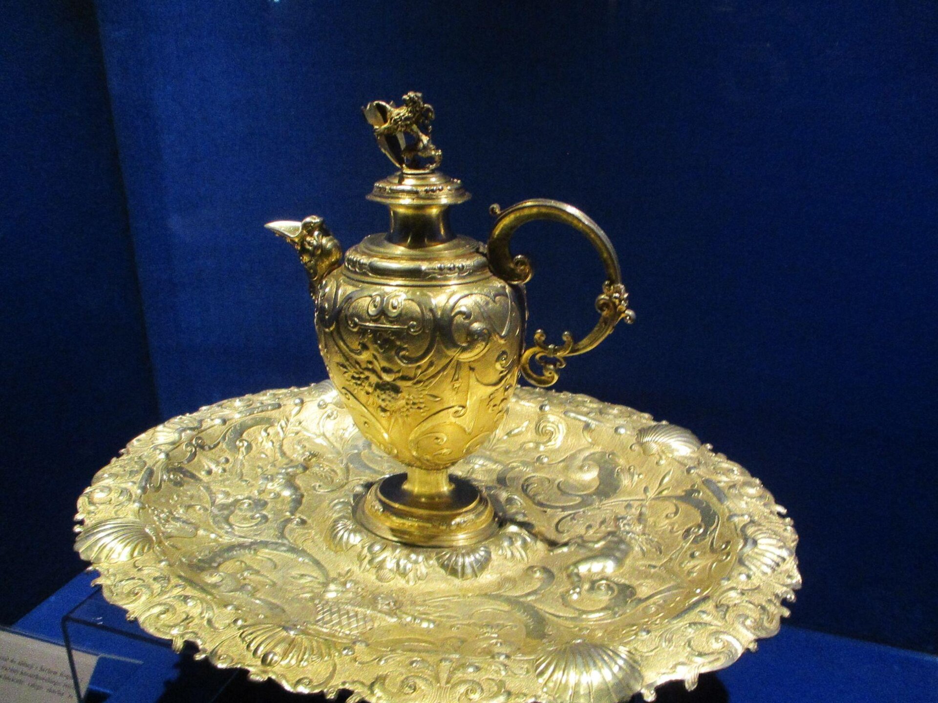 Na zdjęciu fragment skarbu odkrytego przez prof. Chudziak przechowywany w Muzeum Okręgowym w Toruniu. Widać bogato zdobioną tacę metalową a na niej stojący zamykany  dzban. 