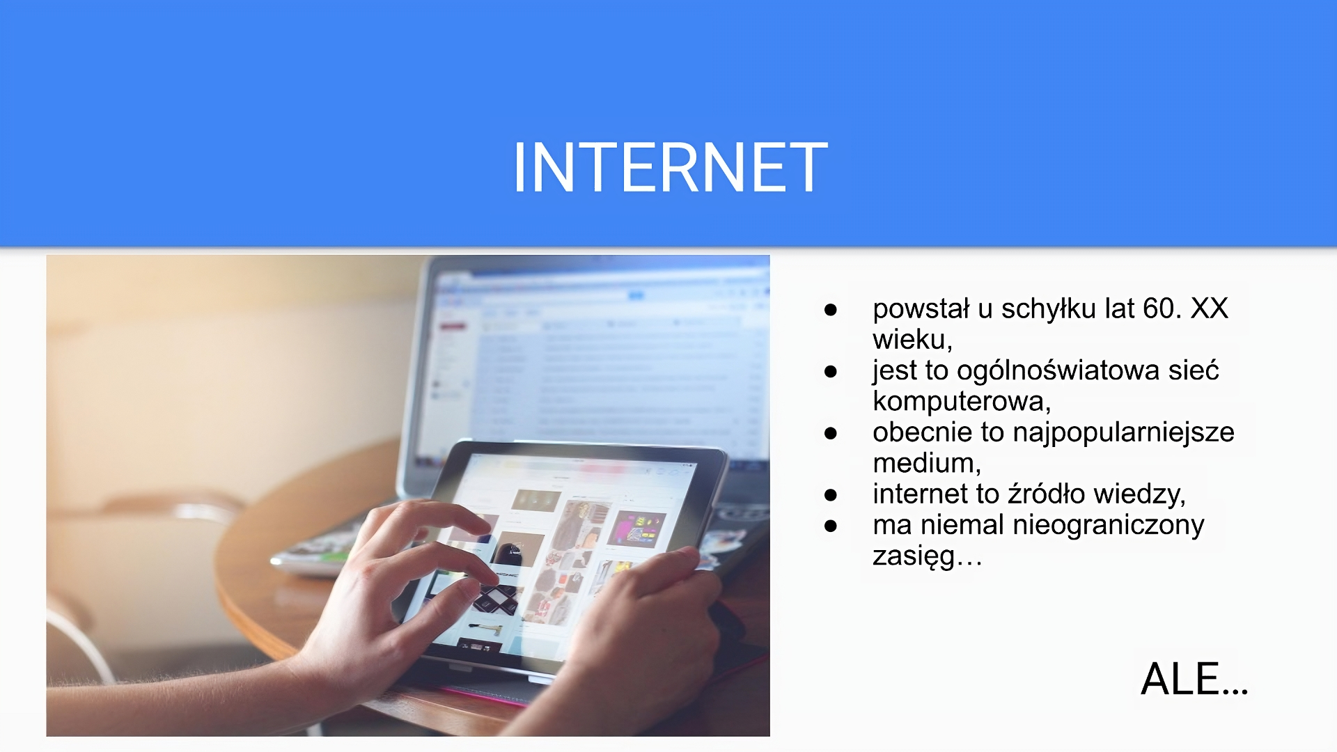 Niebiesko‑biały slajd na którym znajduje się nagłówek: „Internet”. Poniżej czarne napisy: „powstał u schyłku lat 60. XX wieku, jest to ogólnoświatowa sieć komputerowa, obecnie to najpopularniejsze medium, internet to źródło wiedzy, ma niemal nieograniczony zasięg... Ale...”. Po lewej stronie slajdu znajduje się zdjęcie przedstawiające dłonie dotykające monitora tabletu, na którym wyświetlają się kolorowe okienka. W tle widać włączony monitor komputera.