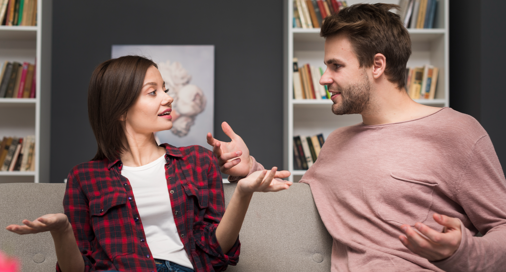 Ilustracja przedstawia mężczyznę i kobietę rozmawiających na kanapie. Oboje patrzą na siebie i mają rozłożona ręce w trakcie dyskusji. Kobieta ma włosy do ramion i rozpiętą koszulę w kratkę a mężczyzna ma krótkie włosy i lekki zarost oraz sweter.