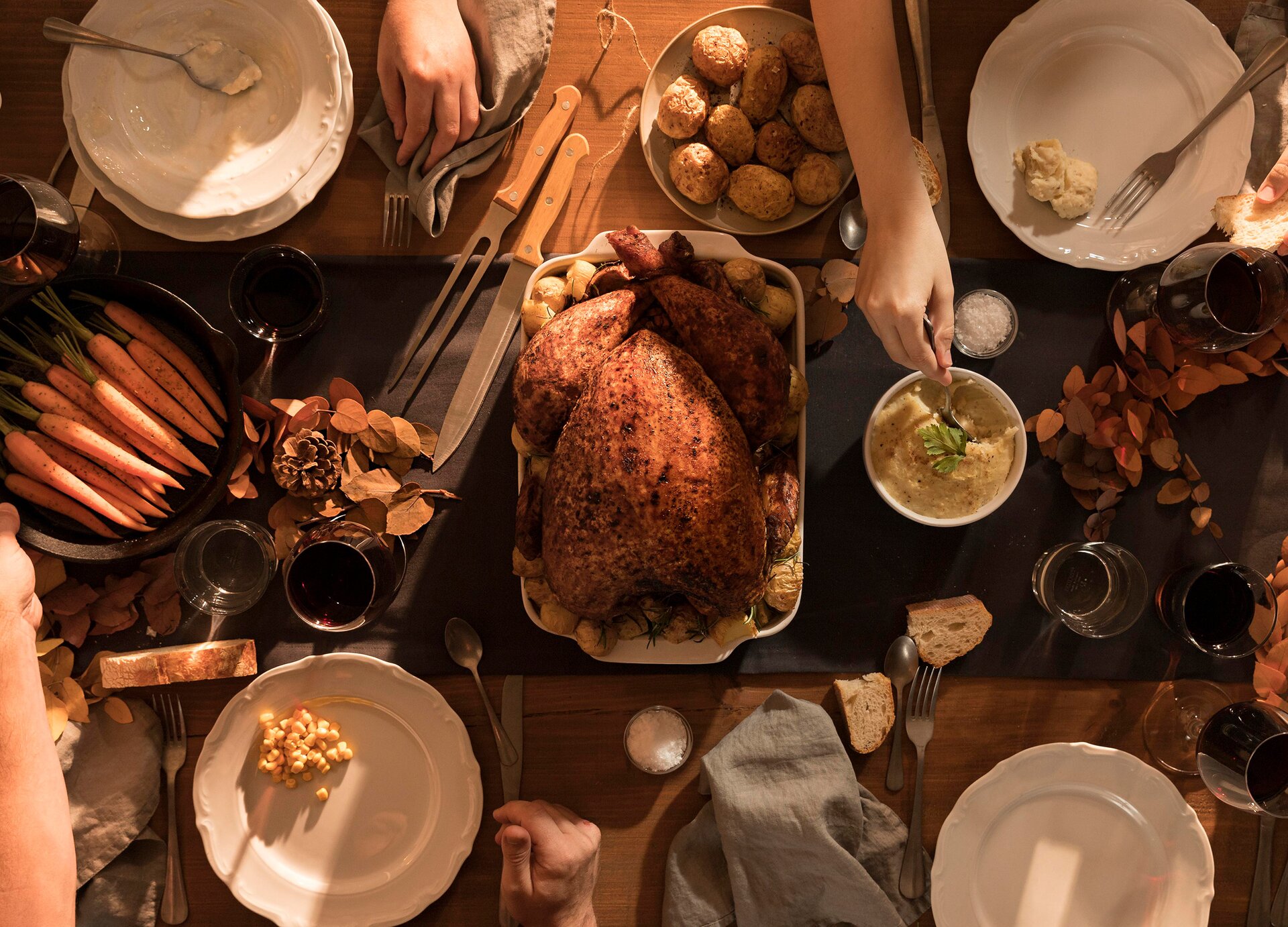 Zdjęcie wykonano z góry. widoczny jest stół, na którym ustawiono pieczonego indyka oraz różne przystawki. 