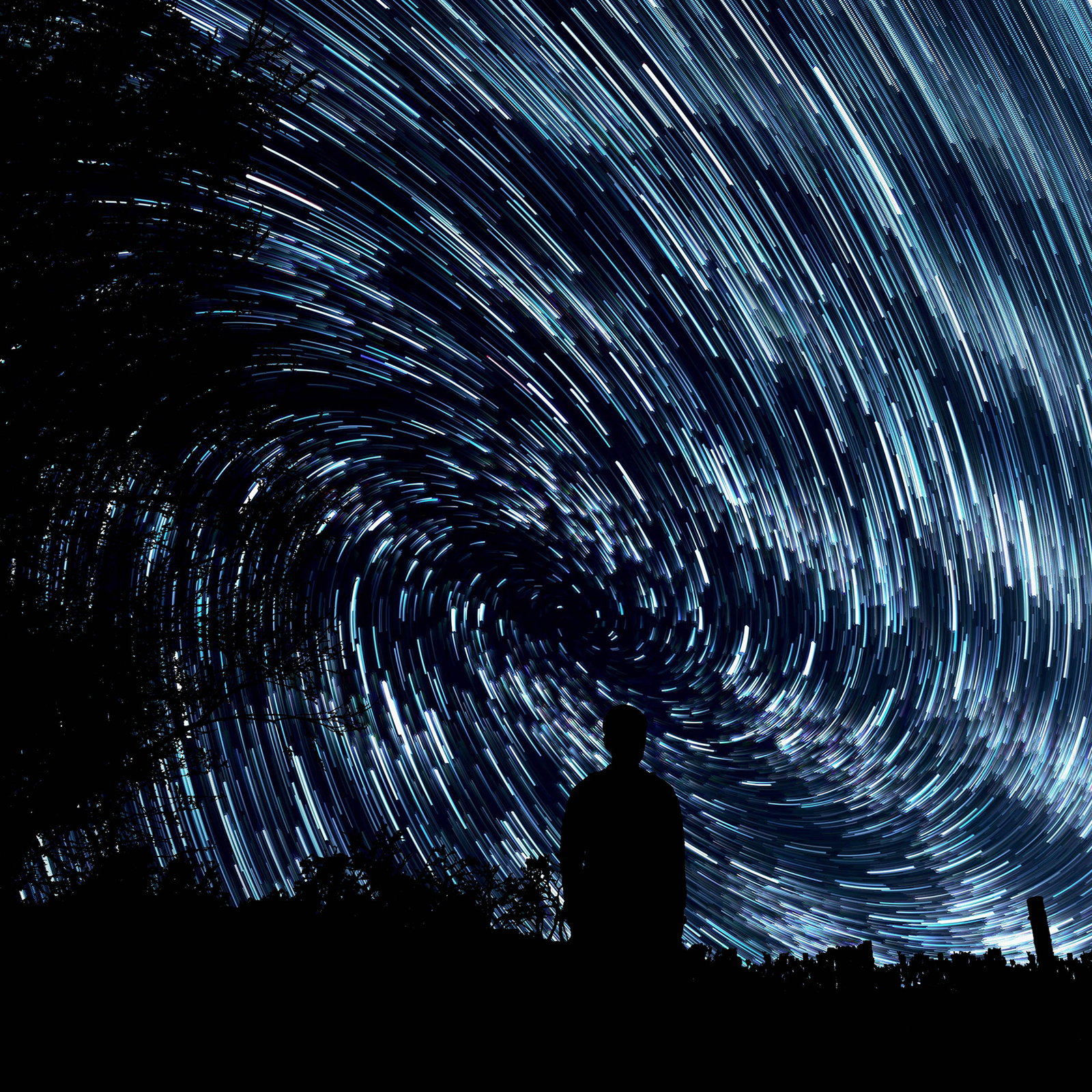 Zdjęcie przedstawia postać stojącą na dworze wpatrzoną w niebo wyglądające, jak gdyby wirowało w kompletnej ciemności wokół niego.