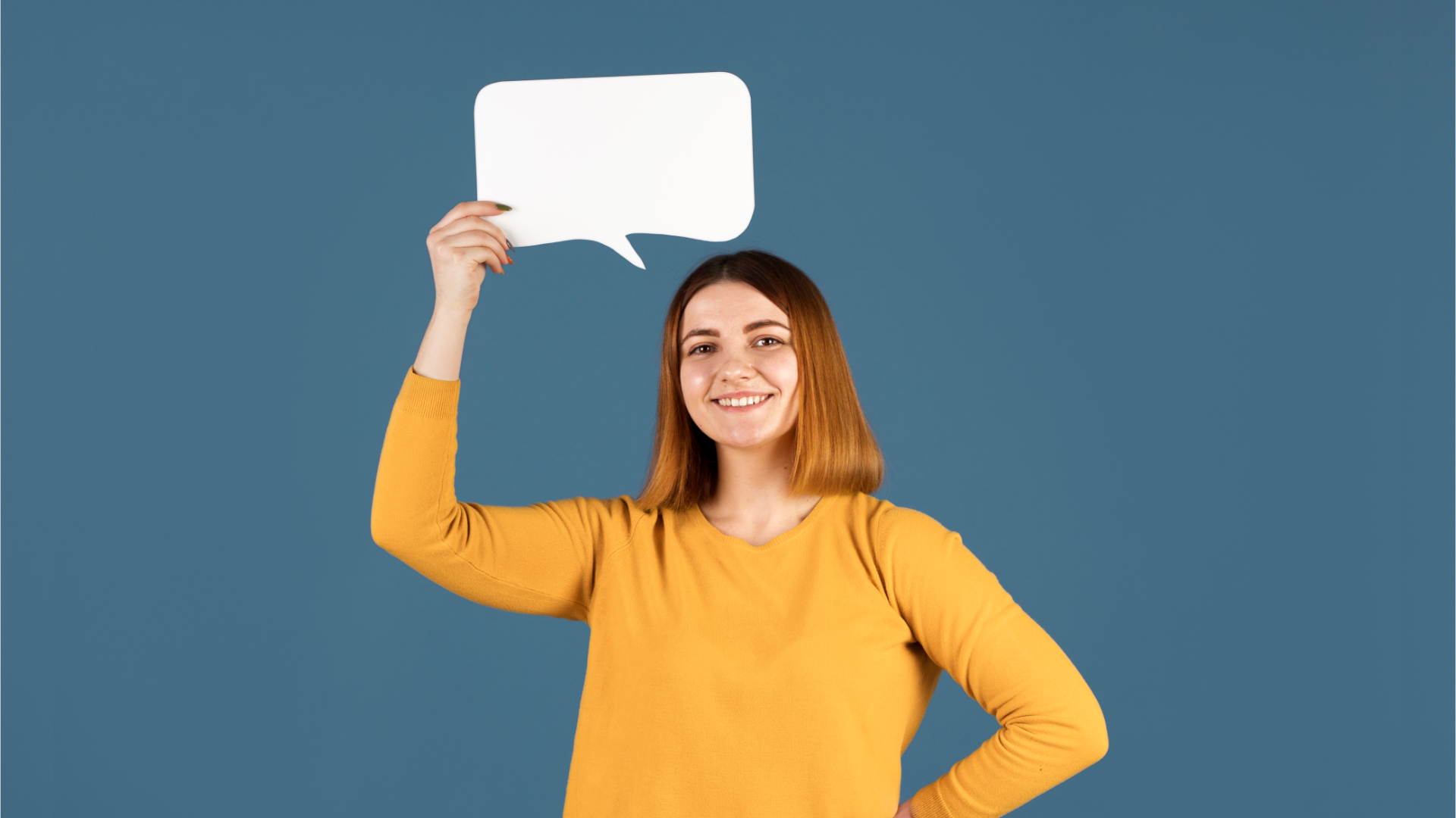 Zdjęcie przedstawia uśmiechniętą, młodą dziewczynę, która trzyma nad głową pusty dymek komiksowy.