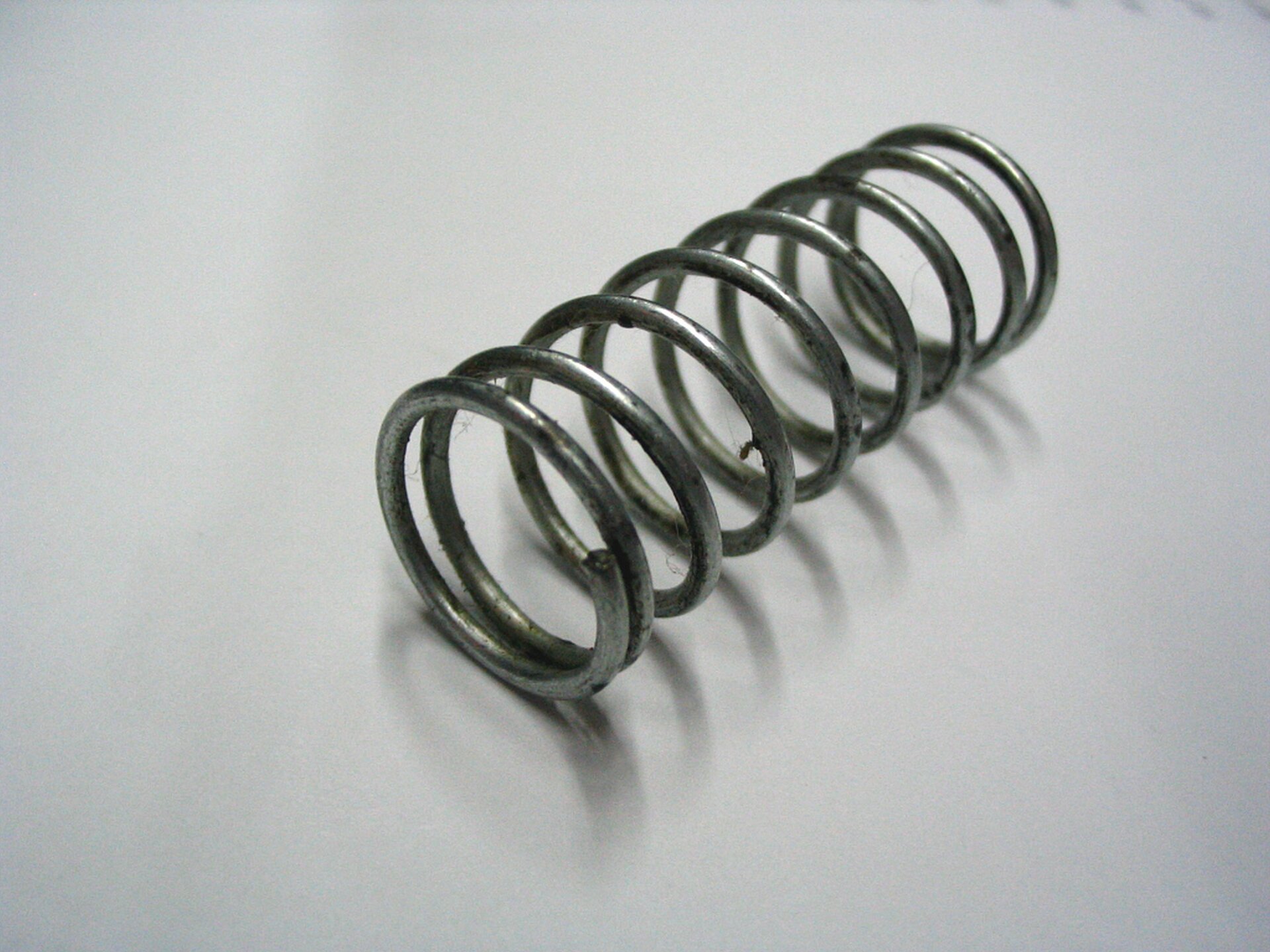 Rys. 1. Zdjęcie poglądowe przedstawia sprężynę leżącą na białym blacie.