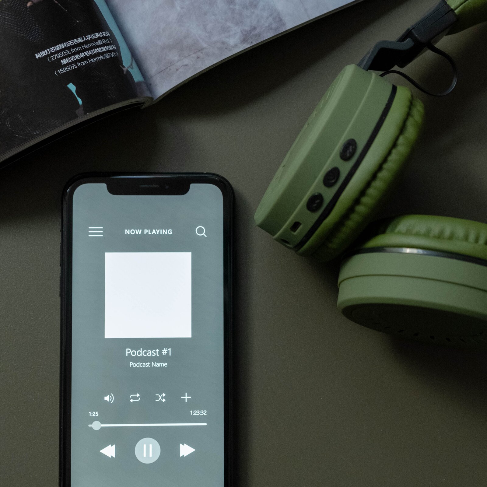 Zdjęcie przedstawia leżący smartfon. Na odblokowanym ekranie jest widoczna aplikacja odtwarzająca podcast.