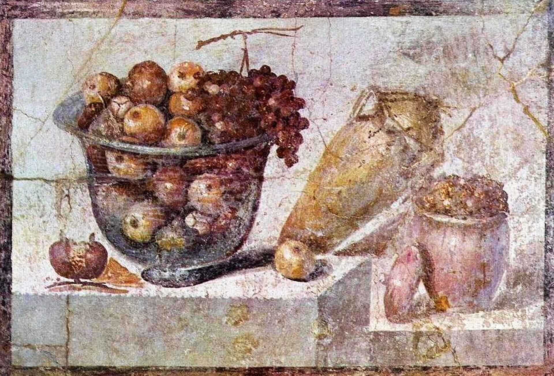 Na ilustracji przedstawiono fresk z Pompejów zatytułowany „Martwa natura z owocami”. Na kamiennym stole stoi szklana misa z granatami i ciemnymi winogronami. Jeden owoc granatu leży rozpołowiony obok misy. Na prawo stoi przechylona żółta amfora z ozdobnym przykryciem. Opiera się ona o stojący poniżej czerwony dzban, wypełniony po brzegi. Stan fresku nie pozwala ustalić zawartości naczynia.