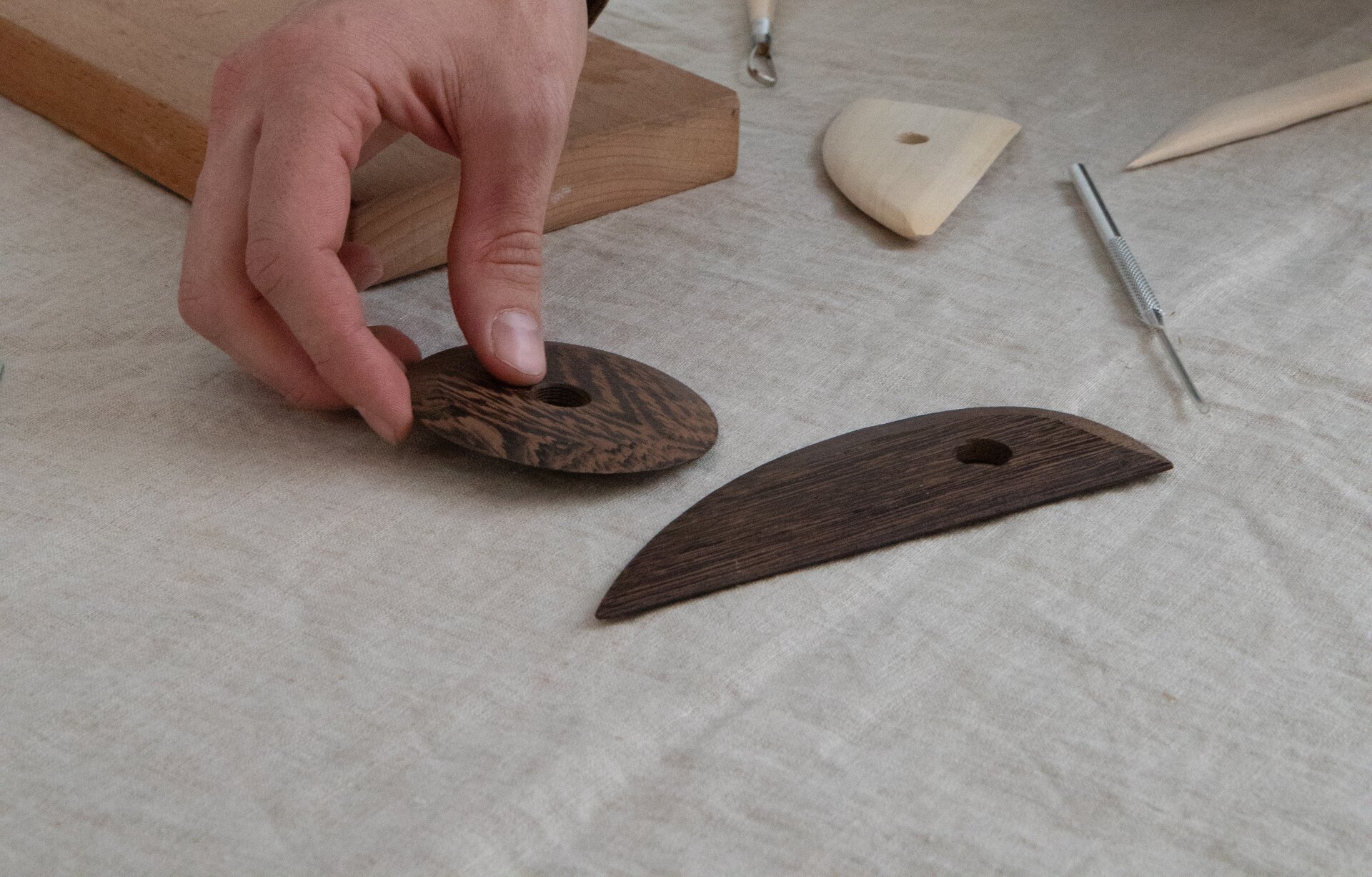 Zdjęcie przedstawia cykliny drewniane, czyli płaskie drewniane elementy z dziurką w środku. Jedna z nich jest okrągła, druga jest podłużna - z jednej strony jest zaokrąglona, z drugiej ścięta na prosto.