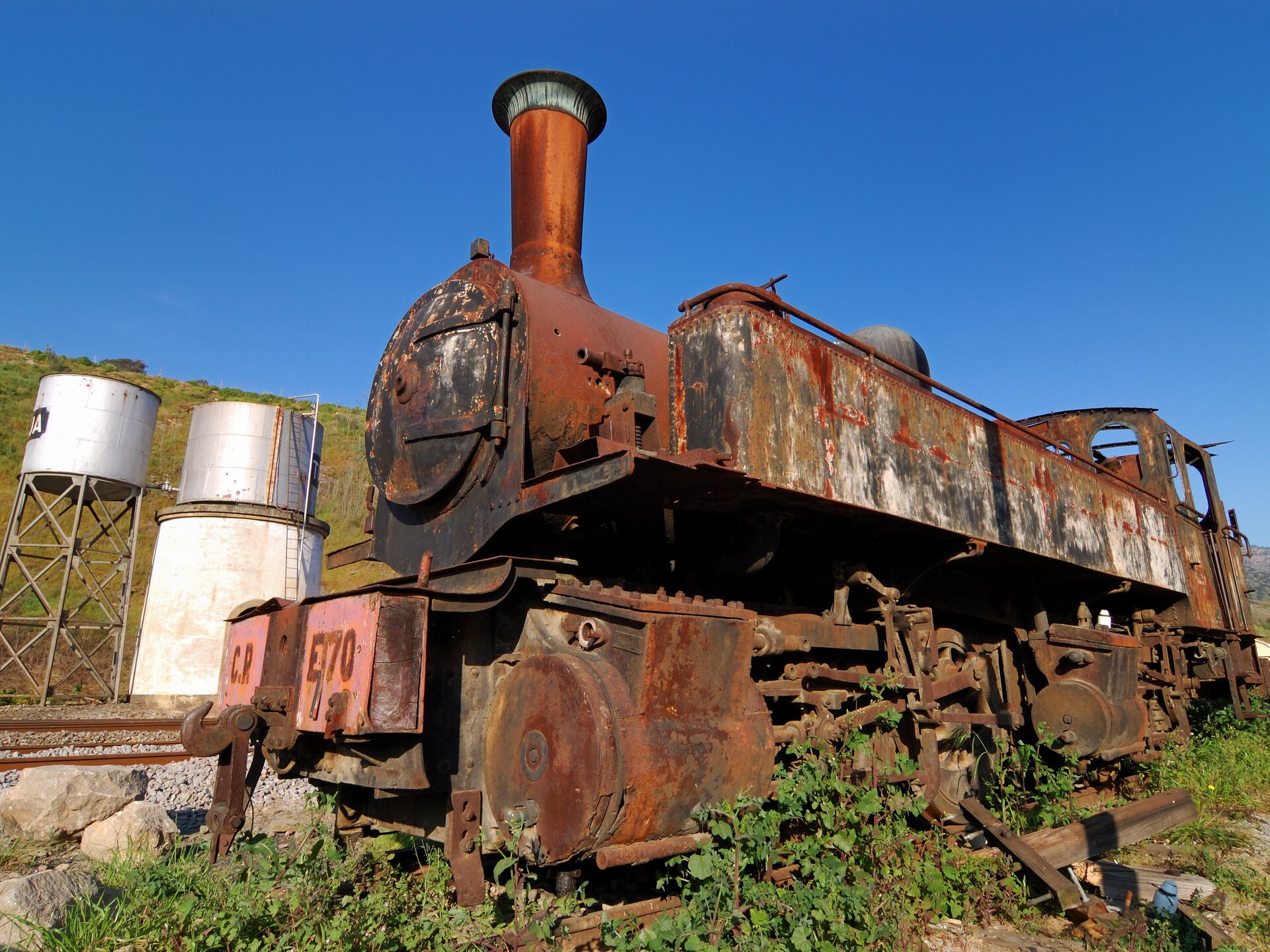 Zardzewiała lokomotywa. Pomarańczowo‑brązowy nalot na metalowej konstrukcji. 
