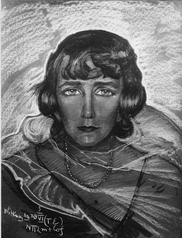 Portret kobiety, która ma półdługie, pofalowane włosy, starannie ułożone wokół owalnej twarzy. Grzywka zakrywa czoło. Jej oczy są duże, brwi wyraziste. Kobieta spogląda przed siebie. Jej nos jest długi i prosty. Ma poważny wyraz twarzy. Na jej szyi wiszą korale.