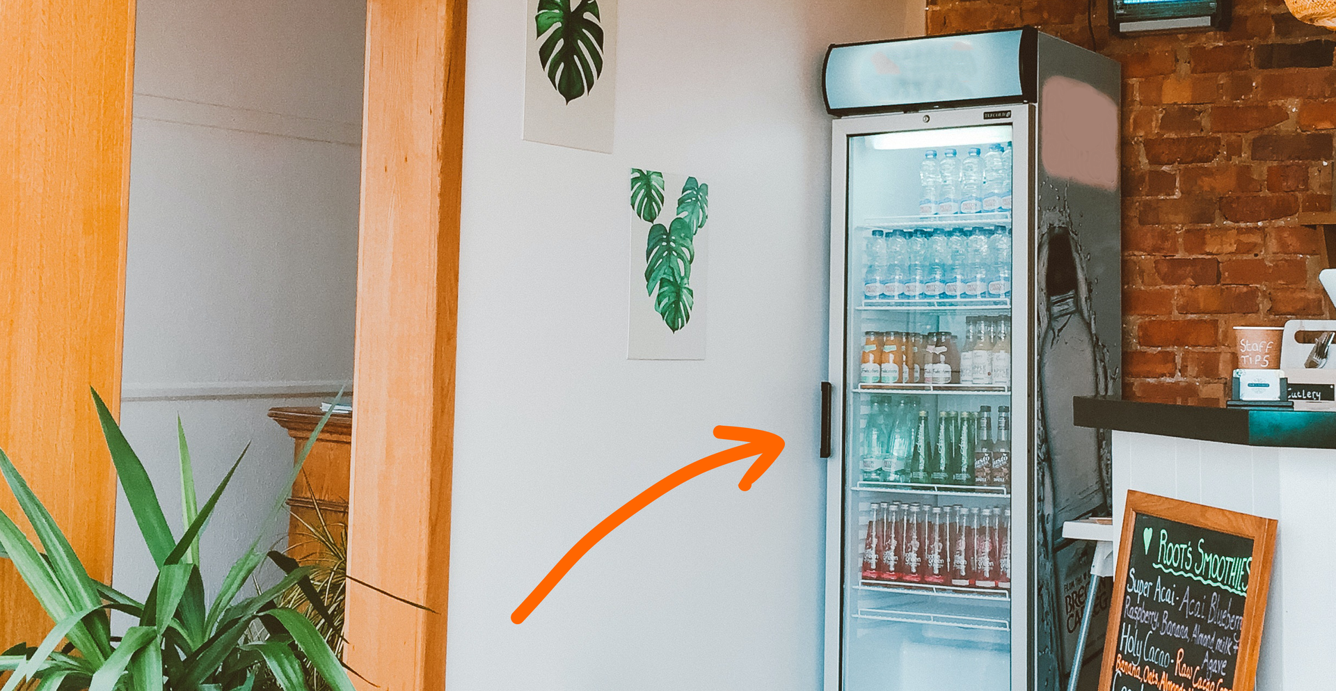 Zdjęcie przedstawia lodówkę z napojami. Lodówka ma przeźroczyste drzwi. Strzałka na ilustracji skierowana jest na lodówkę.