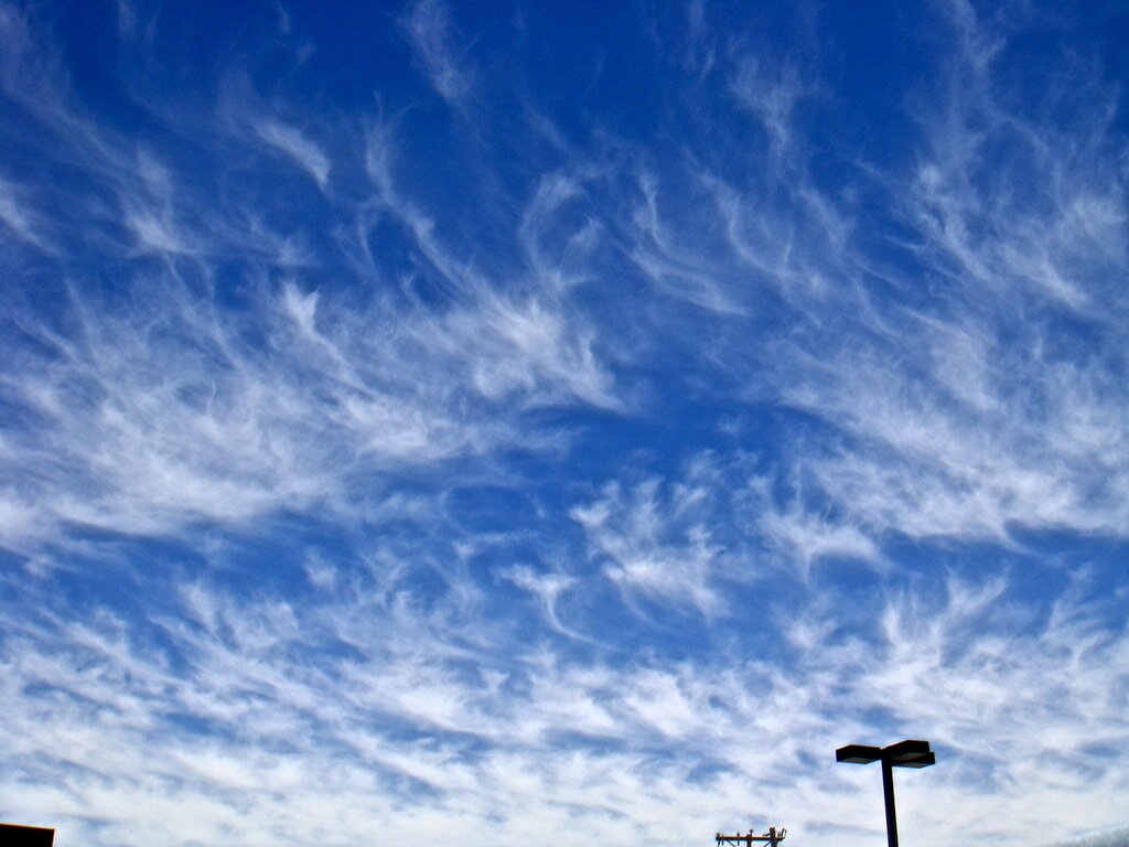 Błękitne niebo pokryte pierzastymi chmurami, które tworzą cienkie pasma.
