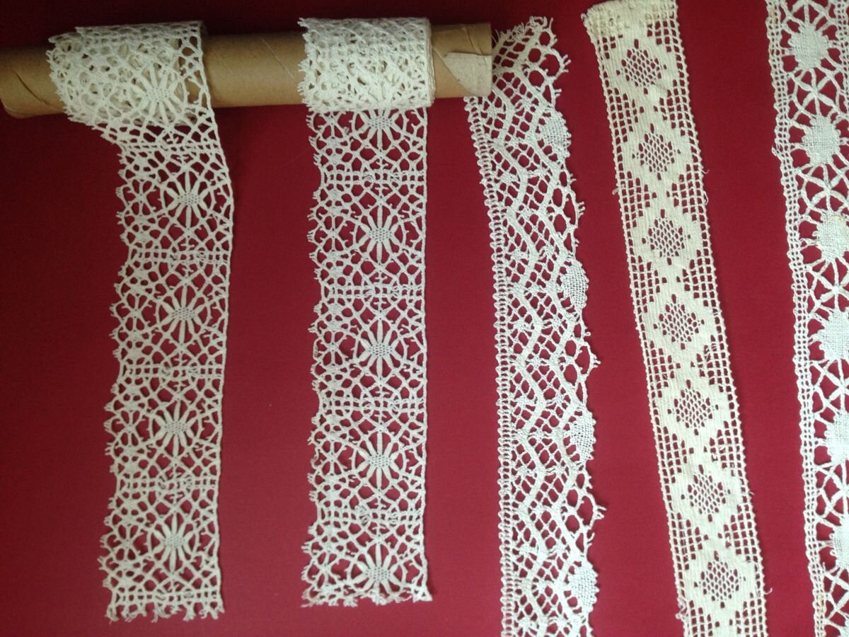 Na bordowym tle znajduje się pięć rodzajów koronek wykonanych z białych nici.