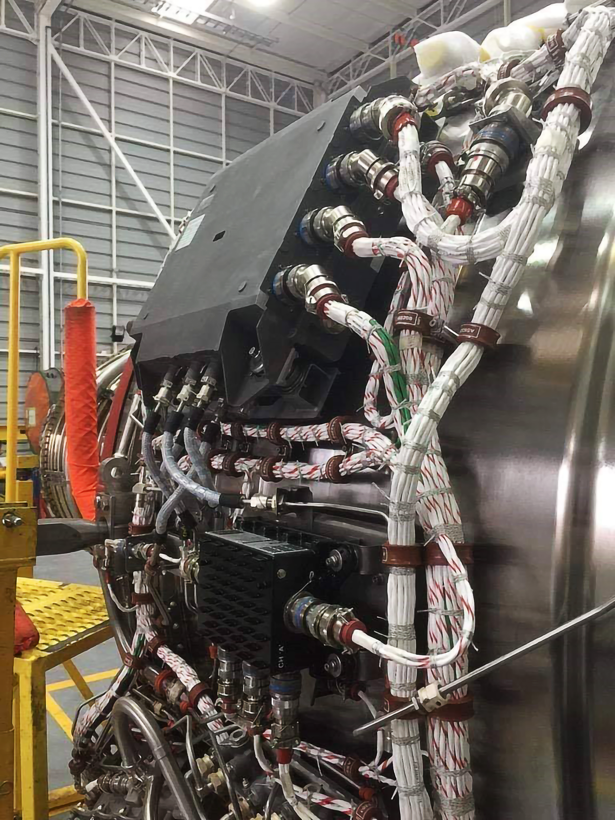 Ilustracja przedstawia zamontowany komputer fadec na turbinowym silniku lotniczym. Zamontowany jest on na zewnętrznej obudowie silnika w przedniej jego części przy wlocie do silnika i podłączony jest do niego różnymi przewodami ze wszystkich stron. 