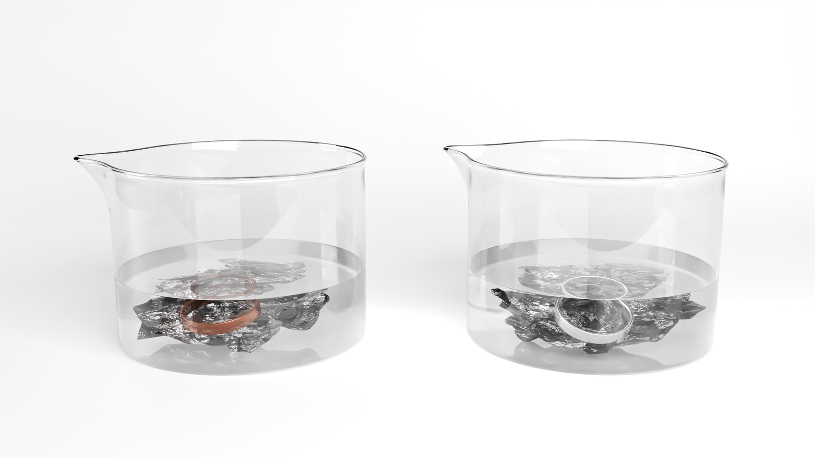 Na ilustracji są dwie zlewki. W każdej z nich jest kawałek srebrnego metalu. W jednej zlewce jest złota obrączka, w drugiej srebrna.   