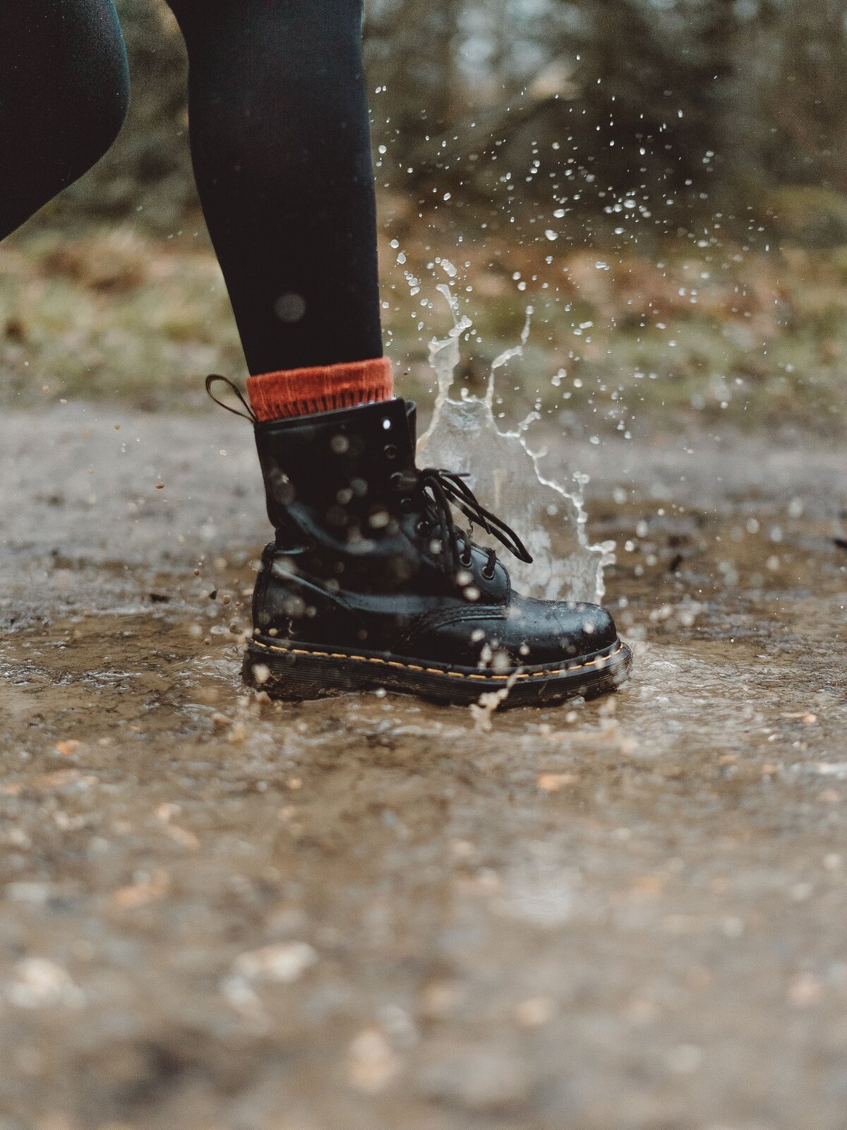 Zdjęcie przedstawia nogę osoby w grubych czarnych rajstopach i bucie typu traper. 