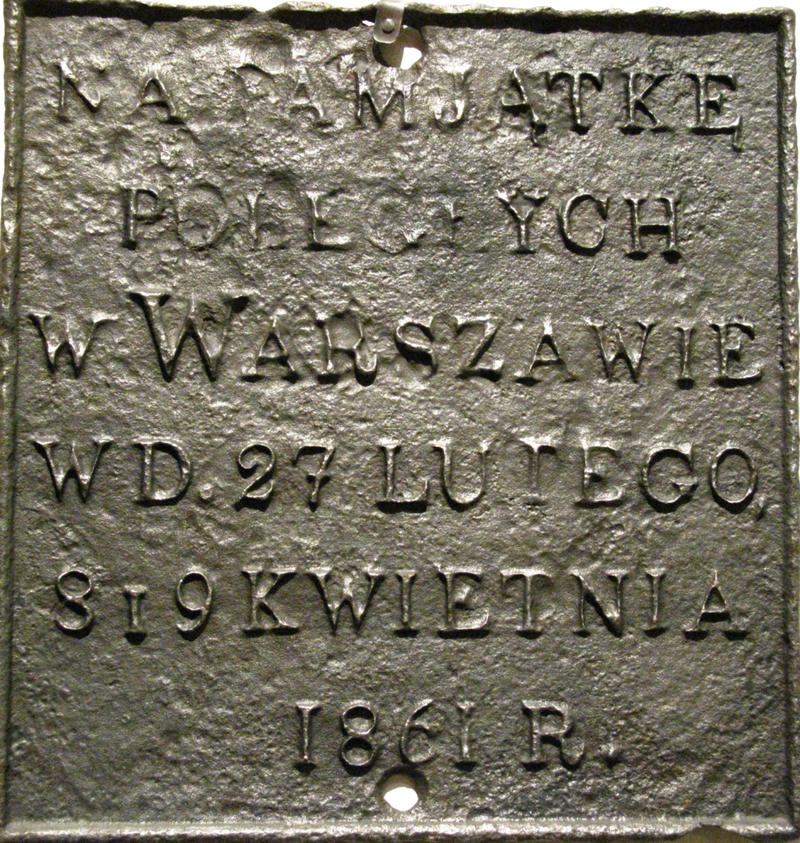 Ilustracja przedstawia tablicę, na której widnieje napis: Na pamiątkę poległych w Warszawie w dniu 27 lutego, 8 i 9 kwietnia 1861 roku.