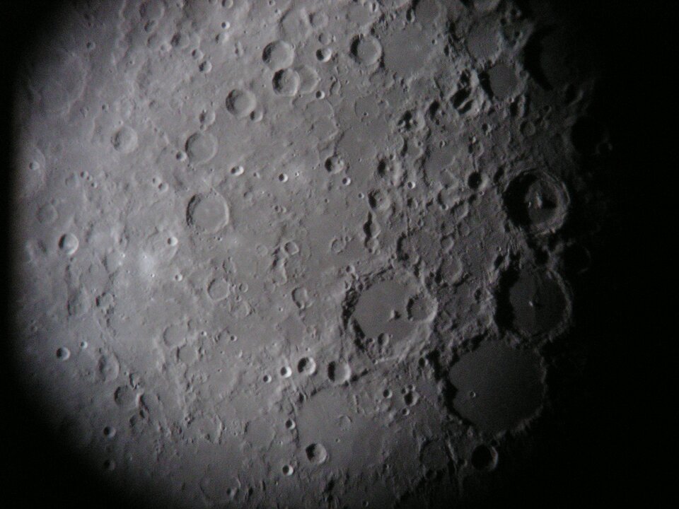 Zdjęcie przedstawia powierzchnię księżyca. Znajdują się na niej różnej wielkości kratery. na zdjęciu księżyc jest szary.
