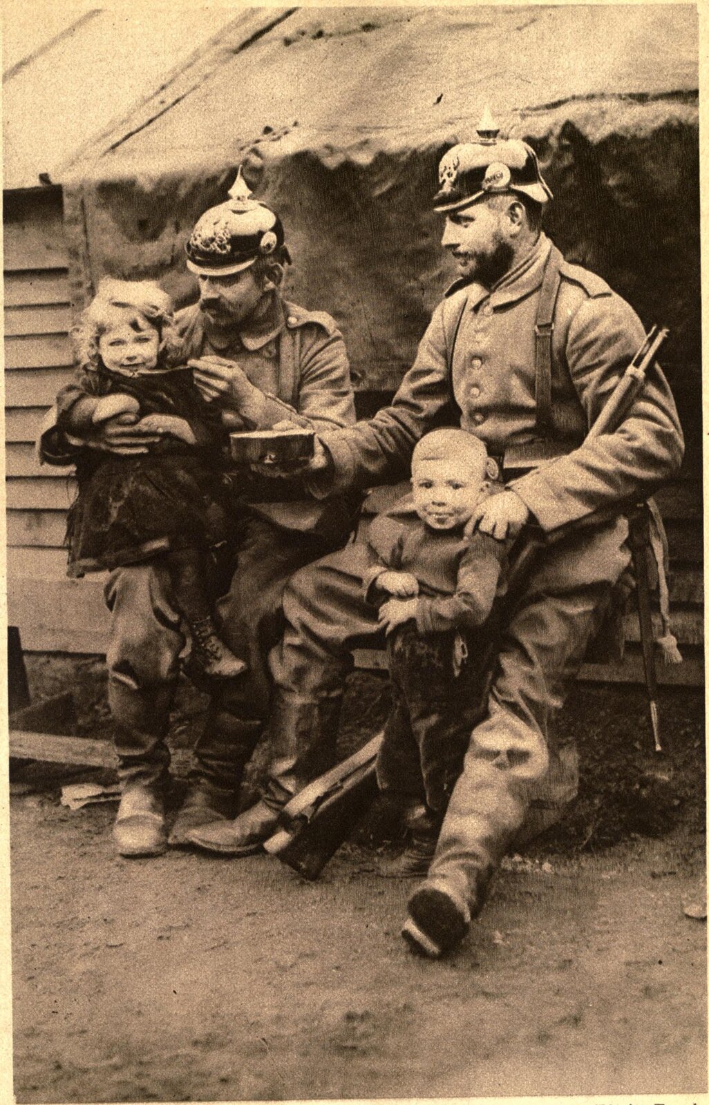 Fotografia czarno-biała przedstawiająca Niemieckich żołnierzy na posterunku w pobliżu Antwerpii, którzy dzielą się jedzeniem z belgijskimi sierotami.