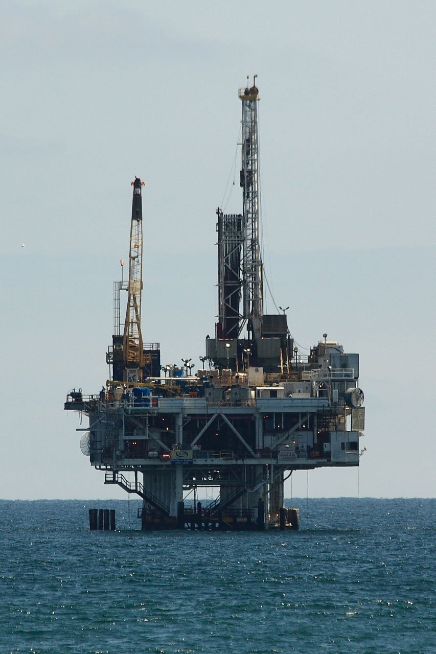 Zdjęcie przedstawia platformę wiertniczą zlokalizowaną na morzu, przeznaczoną do wykonywania odwiertów ropy naftowej. Ma dwie wyższe konstrukcje metalowe. 