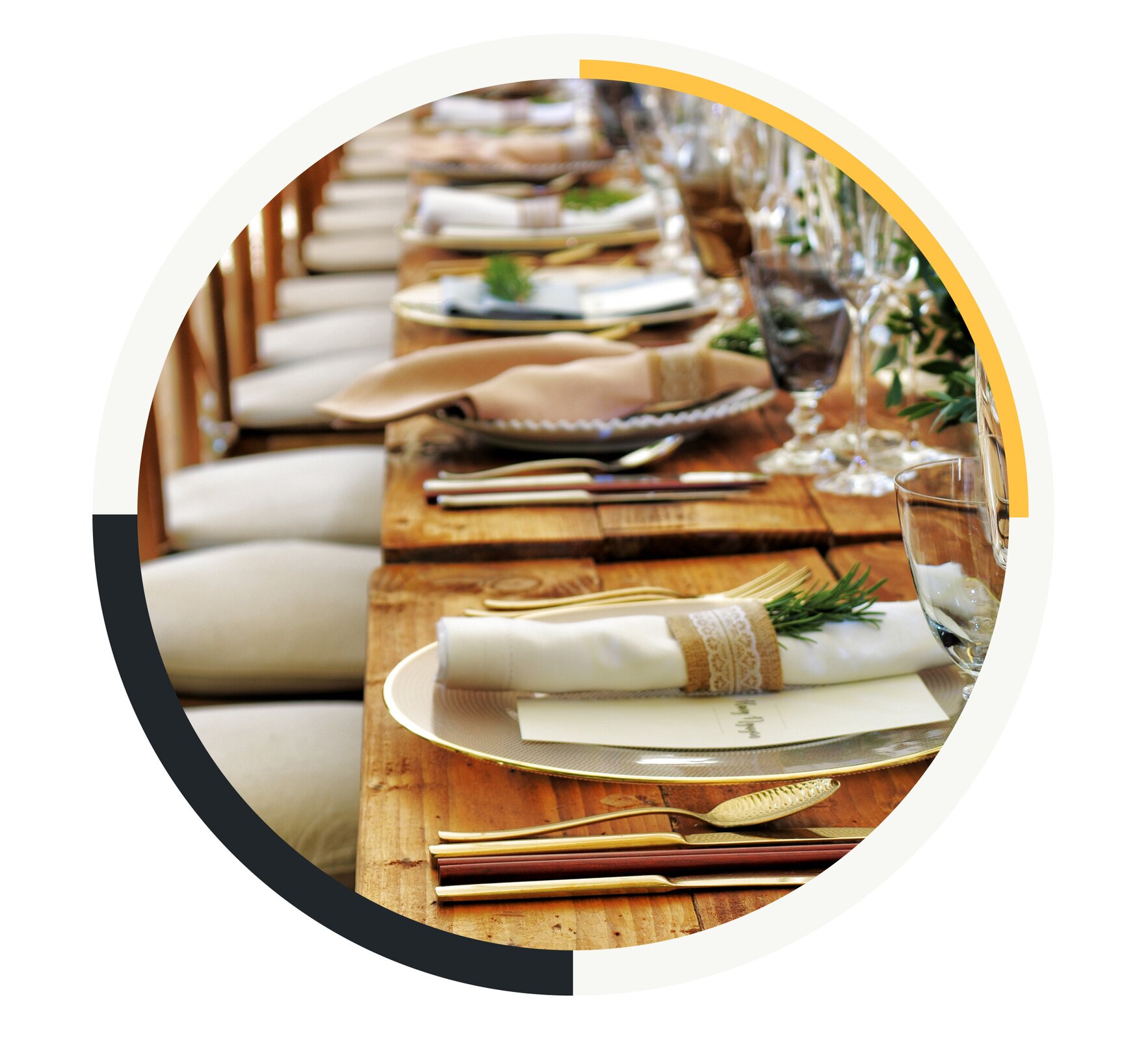 Na zdjęciu znajduje się pasmo zsuniętych ze sobą drewnianych stołów z krzesłami. Na stołach widać elegancką zastawę. Przy każdym krześle na stole leży talerz, na nim ozdobna kartka z imieniem i nazwiskiem gościa, a także zwinięta w rulon serwetka przyozdobiona gałązką jedliny. Po prawej stronie każdego talerza znajdują się złote widelce. Po prawej stronie każdego talerza znajdują się złote łyżki i noże, a także pałeczki służące do jedzenia. Na środku stołów rozstawione są kielichy, kieliszki i dzbanki z ozdobnymi roślinami.