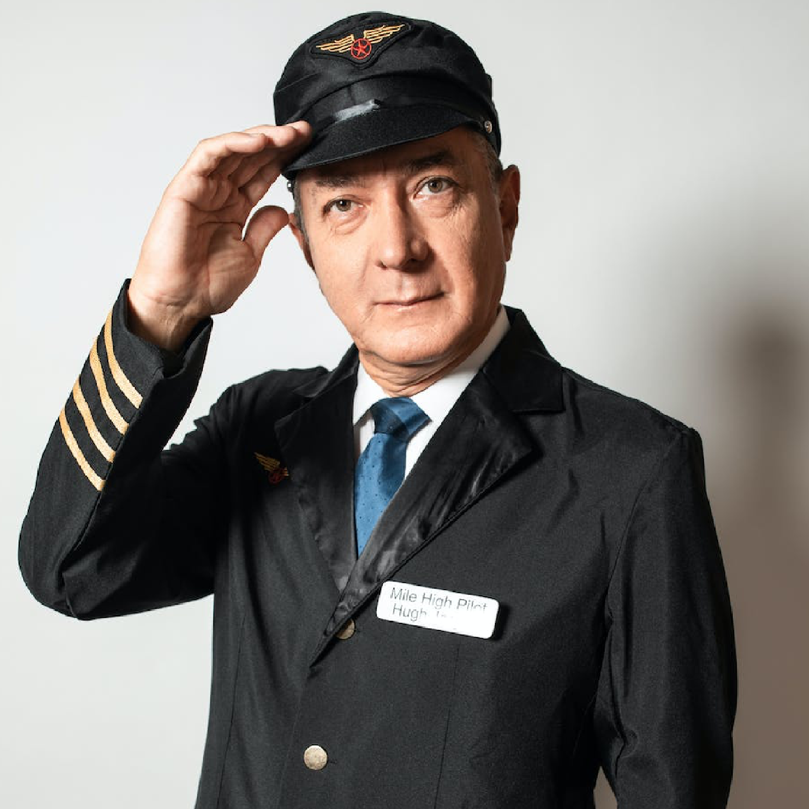 Zdjęcie przedstawia mężczyznę ubranego w strój pilota. Na głowie ma czapkę ze znaczkiem składającym się z dwóch skrzydeł oraz kółka z czerwoną gwiazdą. Ma na sobie również białą koszulę, krawat i marynarkę.  