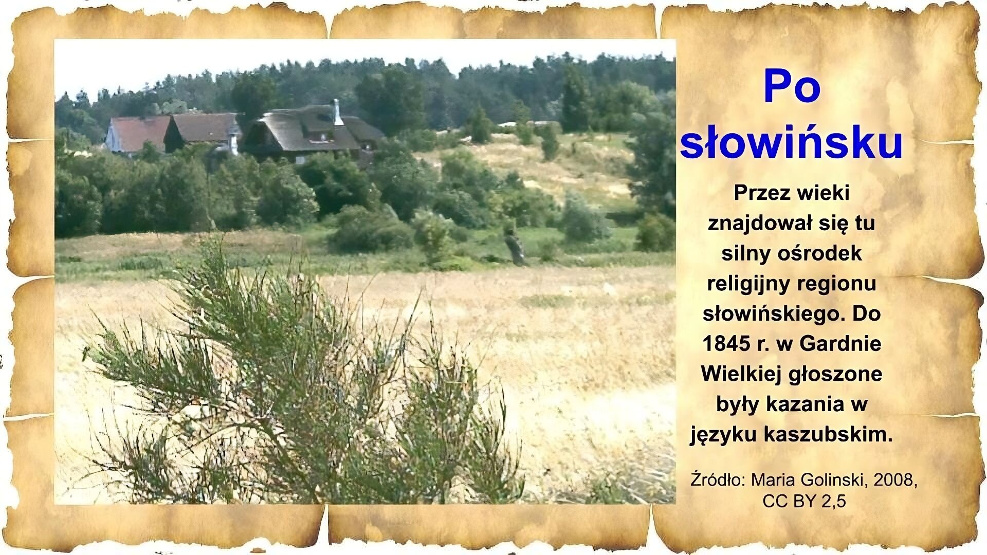 Slajd zawiera napis tytułowy, umieszczony po prawej stornie: Po słowińsku. Poniżej: Przez wieki znajdował się tu silny ośrodek religijny regionu słowińskiego. Do 1845 r. w Gardnie Wielkiej głoszone były kazania w języku kaszubskim. Po lewej stronie slajdu znajduje się zdjęcie. Na pierwszym planie jest pole, za polami rosną niskie drzewa, a za drzewami widać dachy kilku domów. Za nimi rosną wysokie drzewa. Na dole znajduje się napis: Źródło: Maria Golinski, 2008, CC BY 2,5.