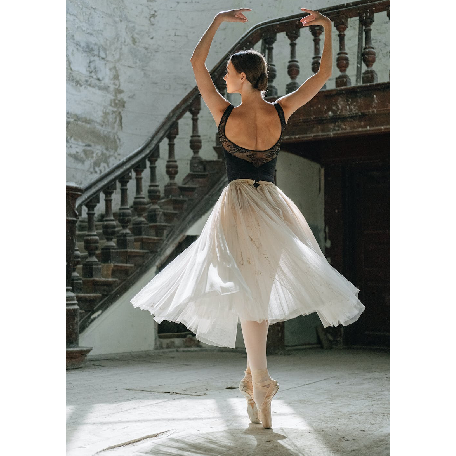 Ilustracja przedstawia baletnicę stojącą na palcach stóp. Na nogach nałożone ma białe pończochy. Wraz z jej obrotem, powiewa półprzezroczysta biała spódniczka. W tle widać stare schody z marmurowymi rzeźbionymi poręczami.