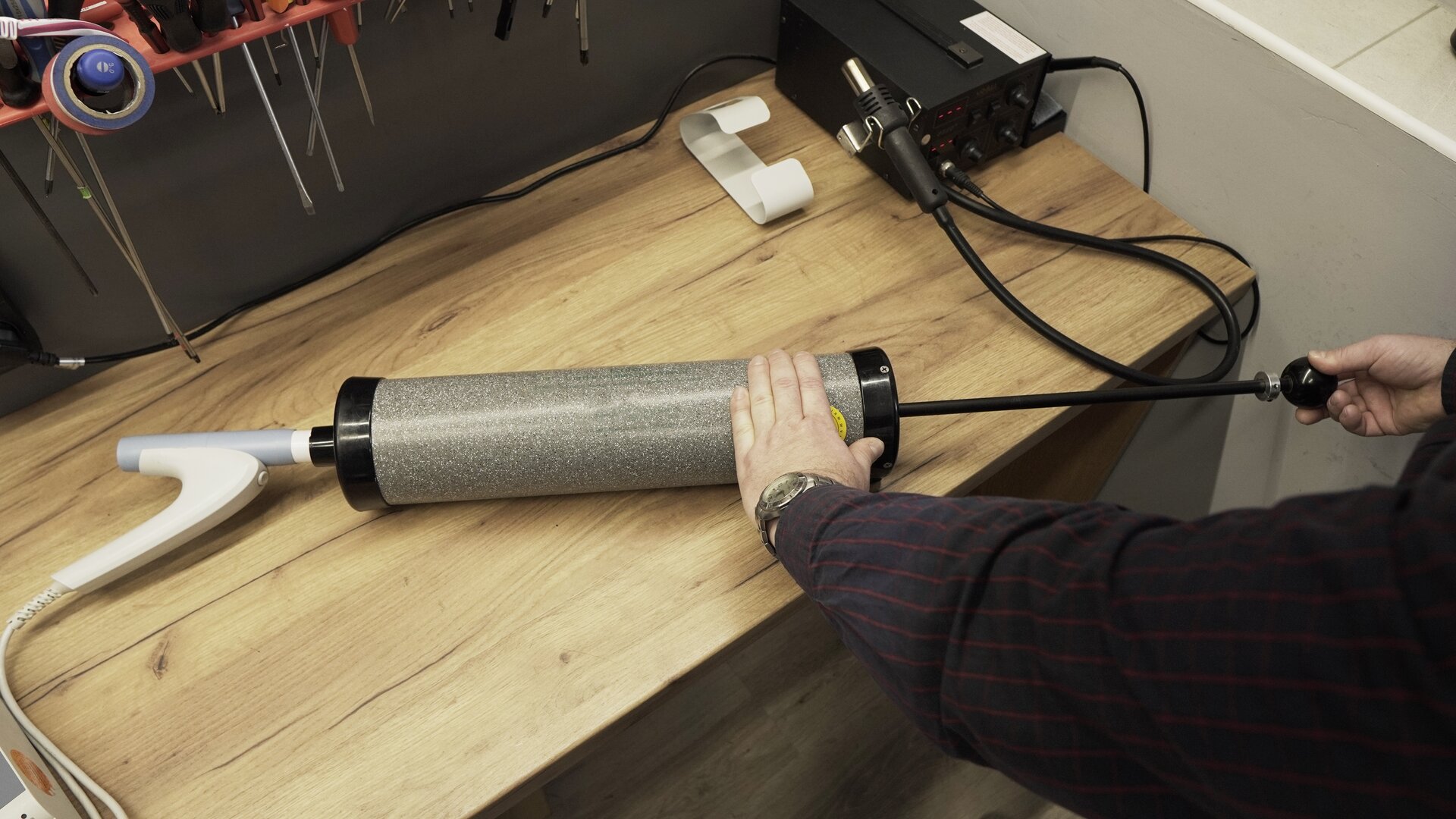 Na zdjęciu technik całkowicie opróżnienia pompę kalibracyjną. Lewą ręką przytrzymuje tubę pompy, druga znajduje się na rękojeści wyciągniętego tłoka.