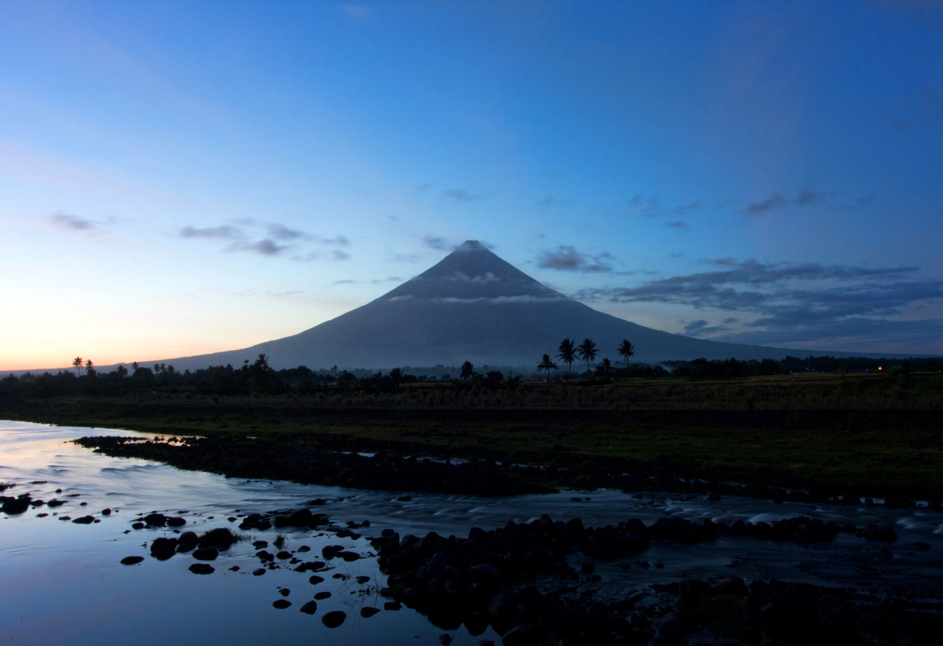Fotografia przedstawiająca Mayon – czynny wulkan na wyspie Luzon na Filipinach. Mayon jest zaliczany do stratowulkanów. Tworzy stożek wulkaniczny o zboczach nachylonych pod kątem 35 do 40 stopni. Na szczycie znajduje się niewielki krater.