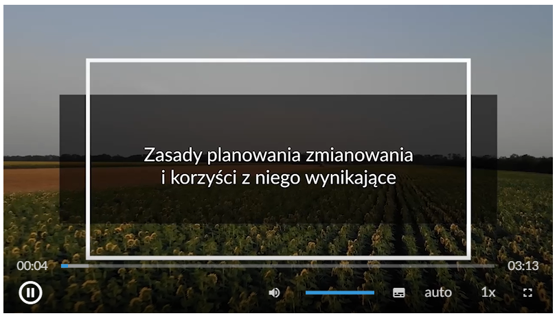 Grafika przedstawia widok okna odtwarzacza filmu. Widoczna jest plansza z napisem: Zasady planowania zmianowania i korzyści z niego wynikające. W tle widoczne jest pole z rosnącymi roślinami. W dolnej części ekranu znajduje się pasek odtwarzania. 