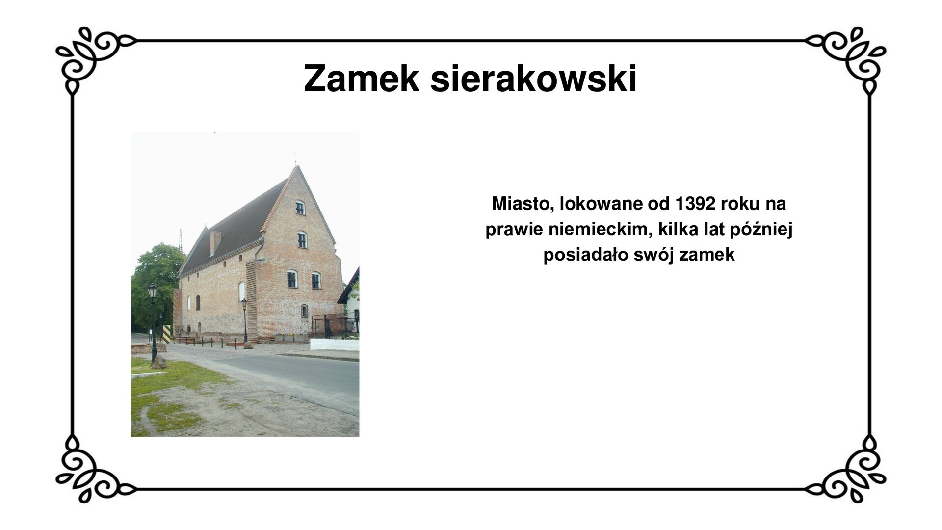 Biała plansza z ozdobną ramką. Tytuł slajdu: Zamek sierakowski. Po lewej stronie ilustracja  przedstawiająca zabudowę zamku sierakowskiego. Konstrukcja budynku ceglanego, uchwycona okiem obiektywu od strony narożnej, z wysokim szczytem bocznej ściany zakończonej łukiem ostrym. Dach dwuspadowy, widoczny w dachu komin. Otwory okienne podłużne o łukach pełnych, w które wpasowano prostokątne okna, dwa na bocznej ścianie trwale zasłonięto. Na pierwszym planie droga przy zamku, lampa uliczna bliżej lewej krawędzi oraz bruk przy zamku. Po prawej widoczny fragment zabudowy sąsiadującego z zamkiem domu. Na dalszym planie drzewa. Po prawej stronie slajdu napis: Miasto, lokowane od 1392 roku na prawie niemieckim, kilka lat później posiadało swój zamek.