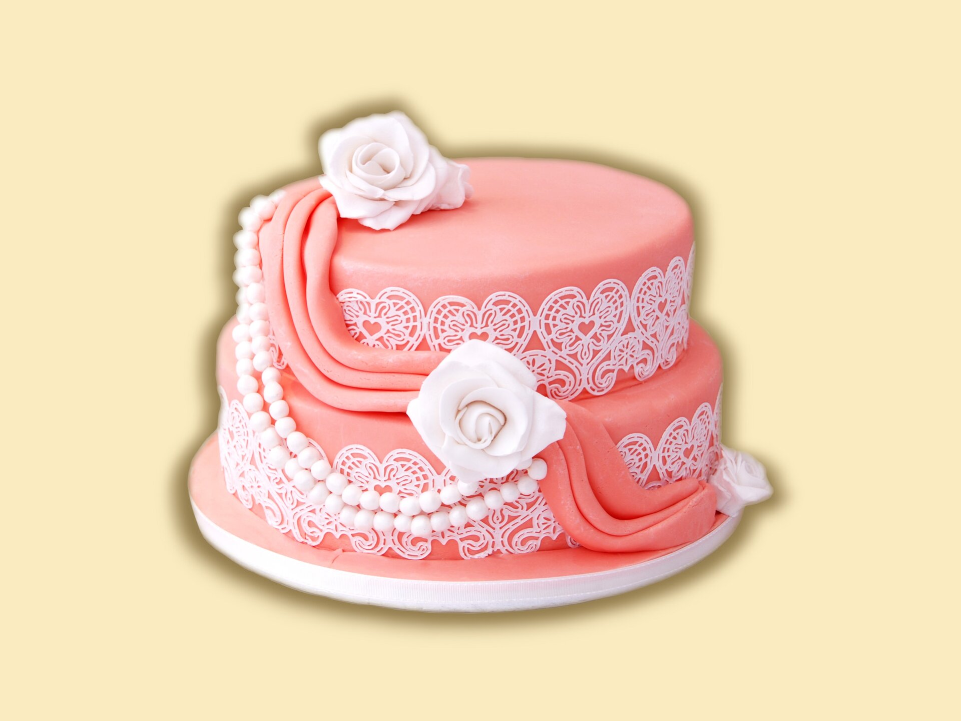 Dwupiętrowy tort urodzinowy, dekorowany różami, plisą, perełkami i ażurem.