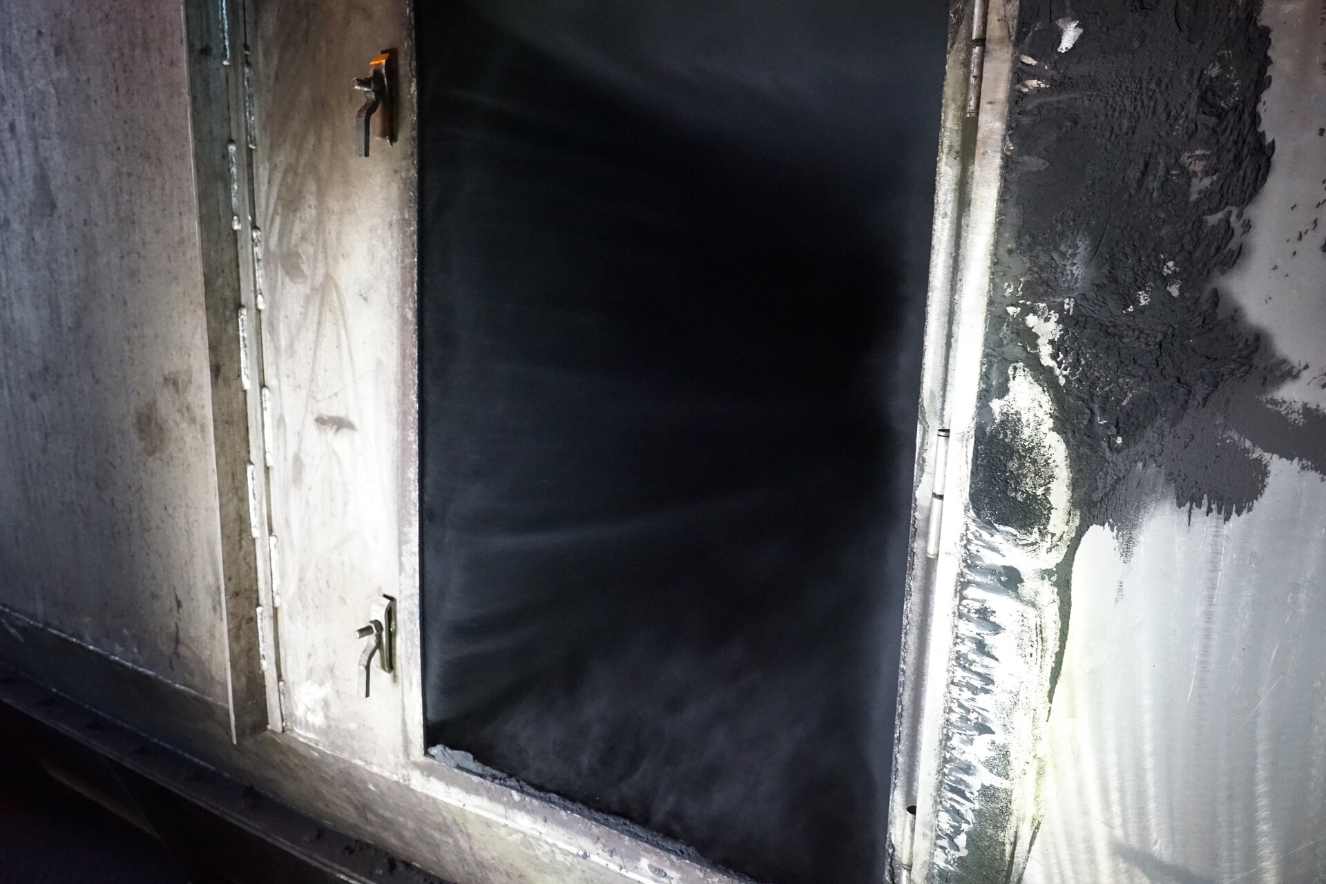 Zdjęcie przedstawia wlot do bębna suszarki. Ma on kształt prostokątny. Widoczny jest zasysany do wnętrza bębna pył wraz z powietrzem. Poniżej zdjęcia znajduje się przycisk multimedialny z nagraniem audio. Treść nagrania jest zgodna z tytułem zdjęcia.