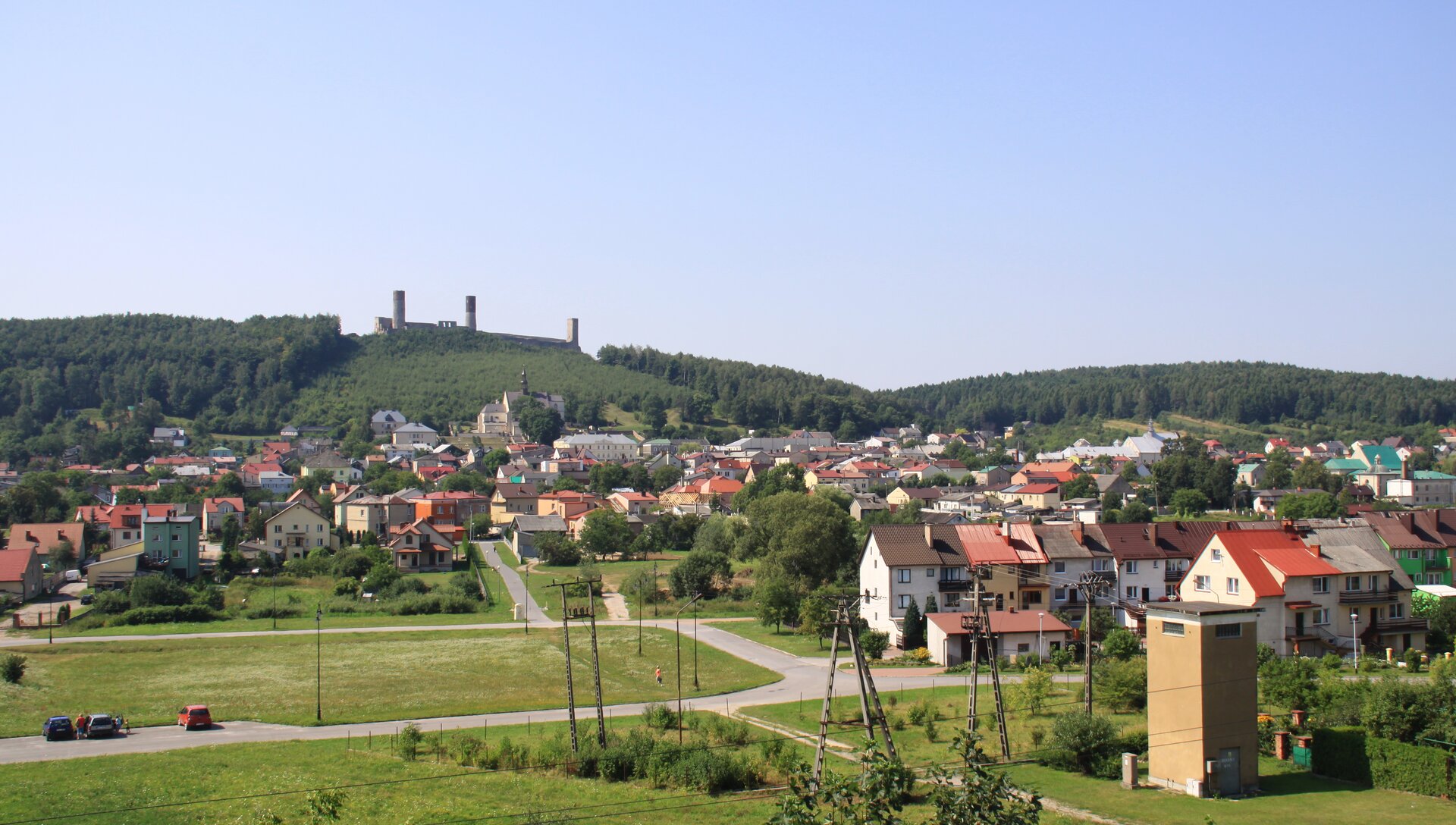 Na zdjęciu zabudowania miejskie, w tle wzgórze z ruinami zamku.