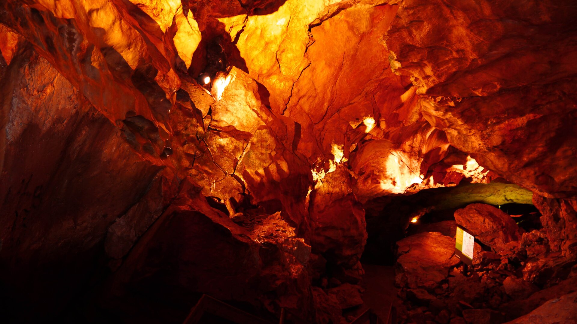 Na zdjęciu znajduje się wnętrze jaskini oświetlone zainstalowanymi lampami. Oświetlenie powoduje, że na zdjęciu jaskinia wygląda na czerwoną.